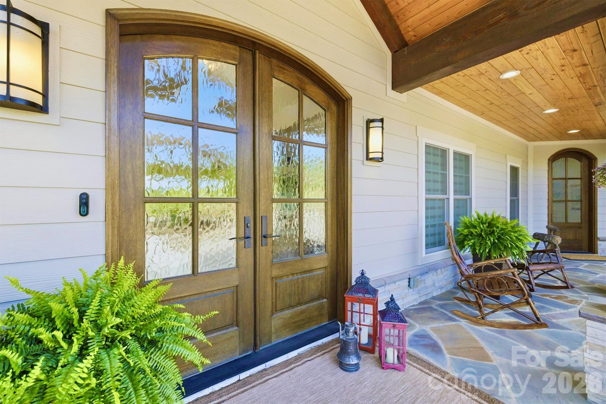 The deep flagstone front porch is a welcoming spot. Arched double french doors with restoration glass open in to the grand foyer, illuminated by a Swarovski crystal chandelier. The entrance on the right opens to the study. - 1506 High Valley Way, Lenoir