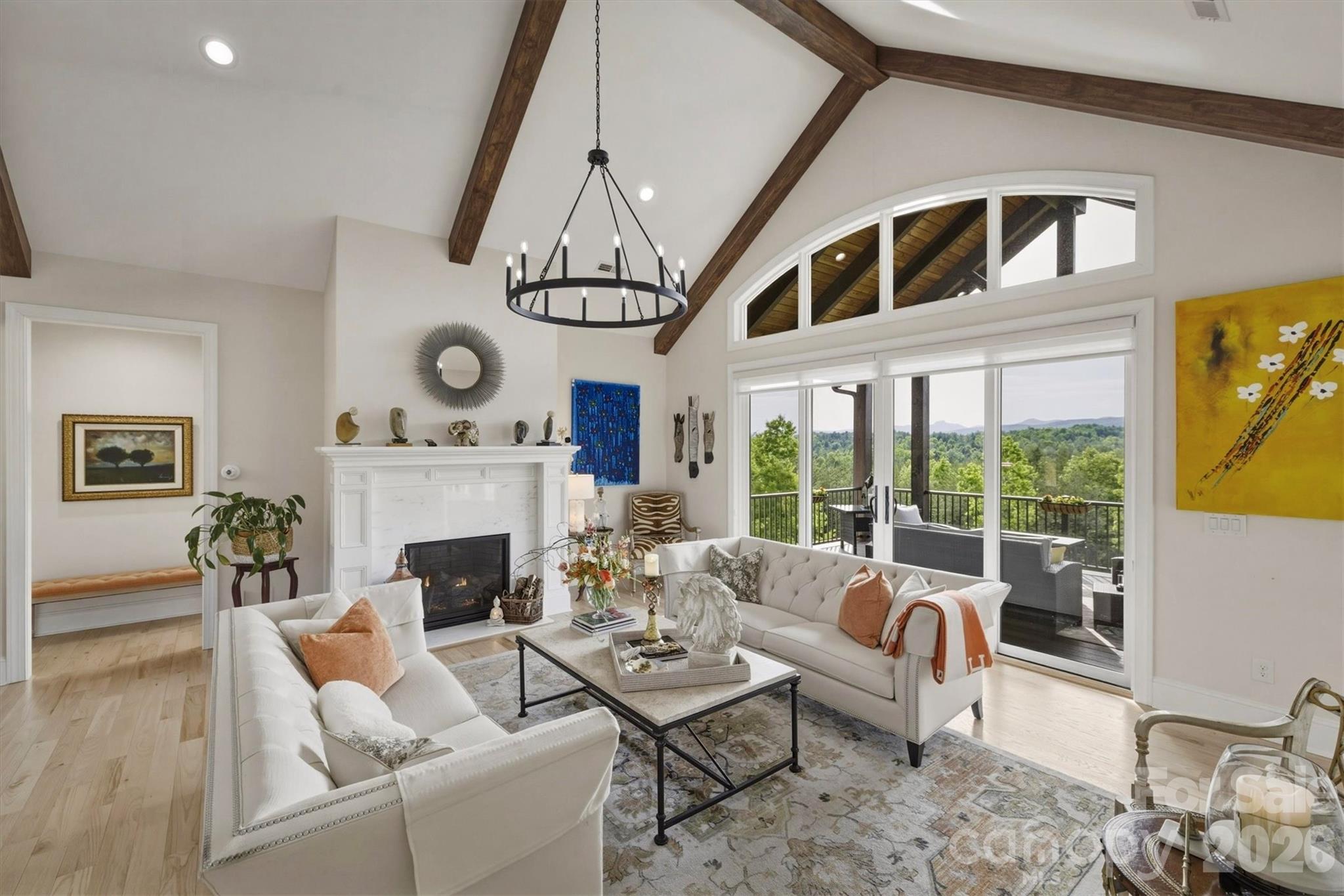 In the living room, cathedral ceilings, accented by walnut stained beams, lead your eyes to floor to ceiling windows and sliding glass doors that frame spellbinding views of Table Rock, Brown Mountain, and more. A wide transom window crowns the space, bathing the interior in more soft, natural light. - 1506 High Valley Way, Lenoir