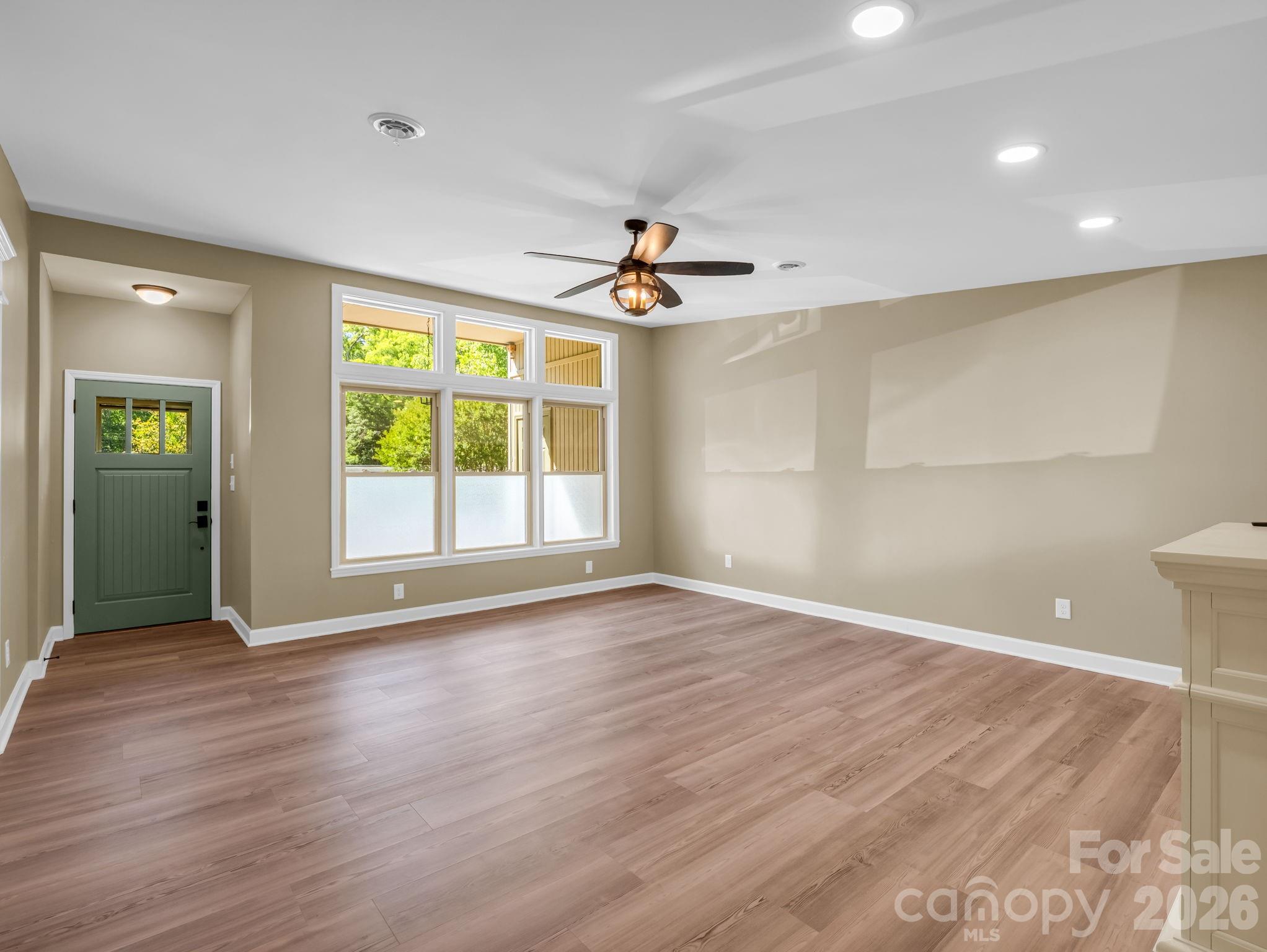 Looking from the hallway toward the front of the living room, the large windows provide lots of natural light. - 44 Jervey Road, Tryon
