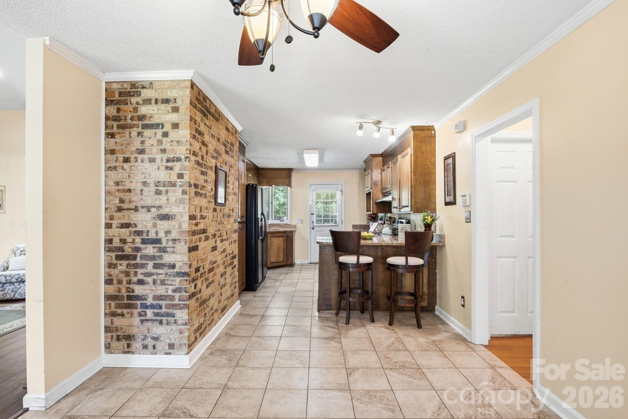 Kitchen featuring granite countertops, breakfast bar, original wood cabinets, and brick fireplace accent. - 1775 Apple Tree Lane, Fort Mill