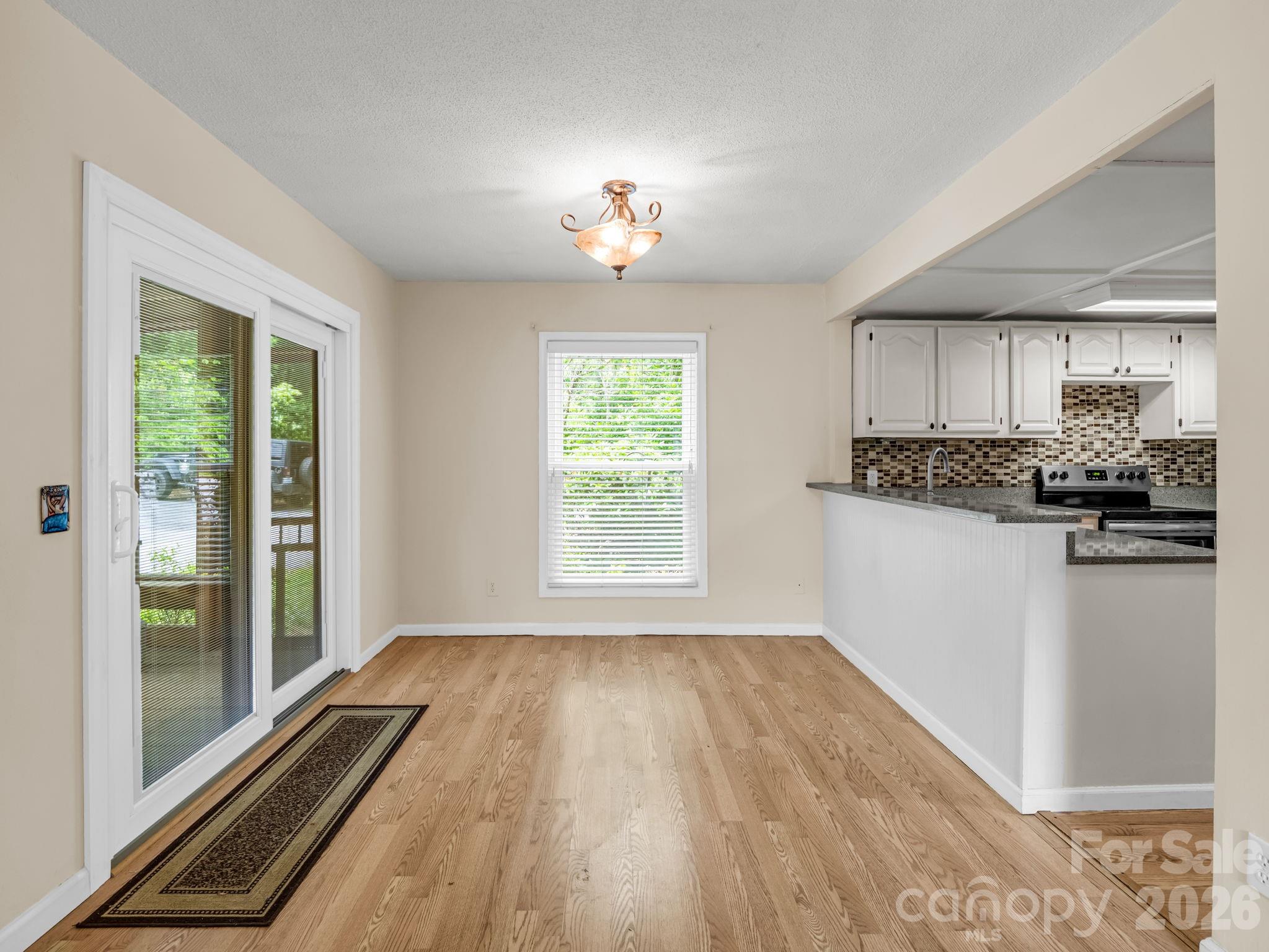 View from living room into dining room, kitchen to the right and screened porch to the lefy - 117 Willow Way, Hendersonville