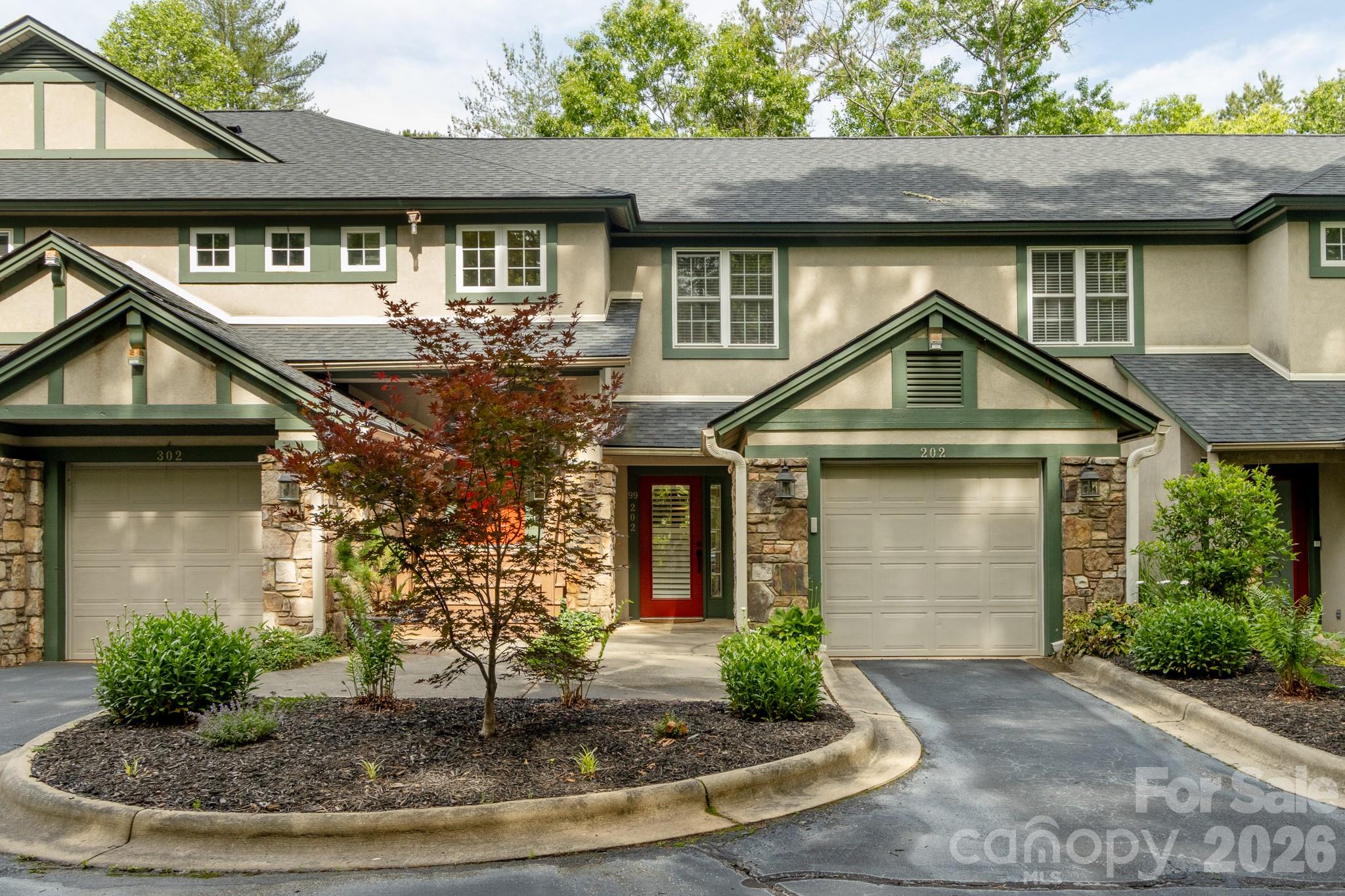 Front Exterior / Building View – Attractive mountain-style condominium exterior featuring stone accents, manicured landscaping, private garage, and low-maintenance living in a peaceful wooded setting. - 99 Ridgetop Circle, Brevard