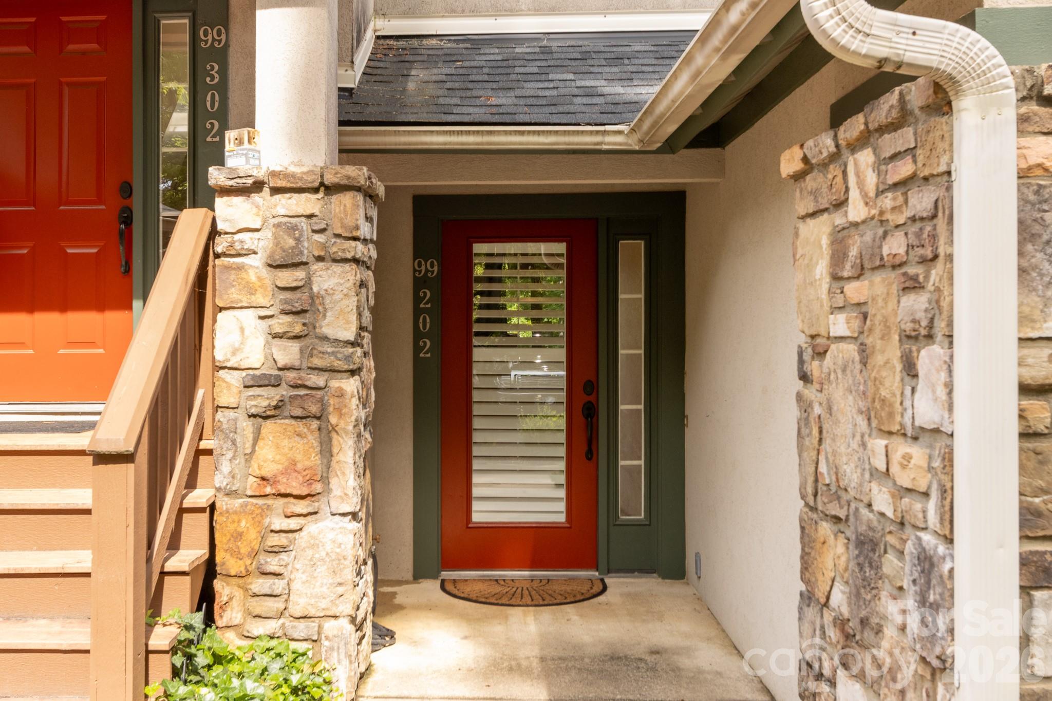 Private Front Entry – Covered front entry with custom-style red door, stone columns, and sheltered access offering both charm and convenience. - 99 Ridgetop Circle, Brevard
