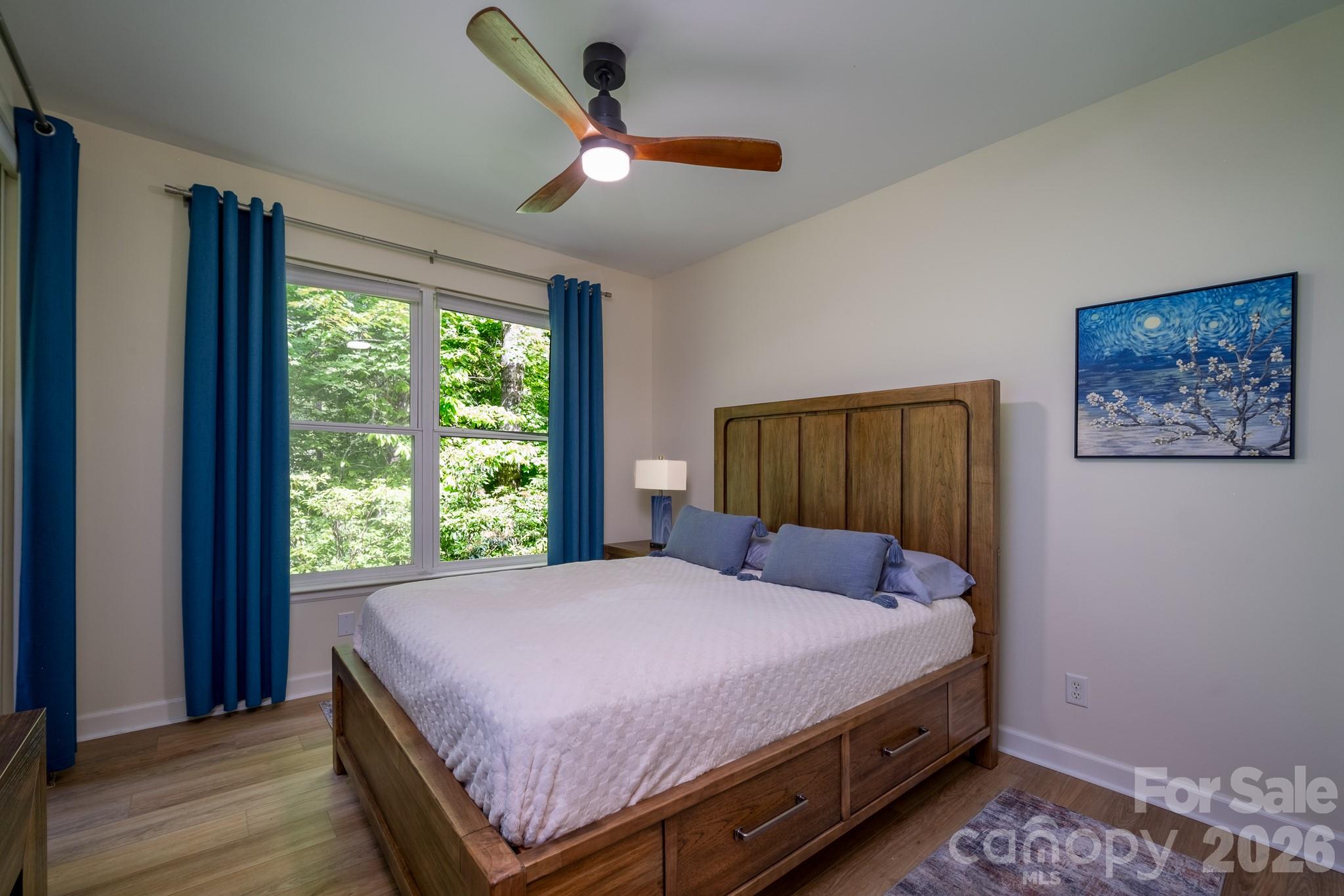 Spacious Guest Bedroom Retreat – Generously sized guest bedroom featuring luxury vinyl plank flooring, modern ceiling fan, and direct access to the screened porch for peaceful wooded views. - 99 Ridgetop Circle, Brevard