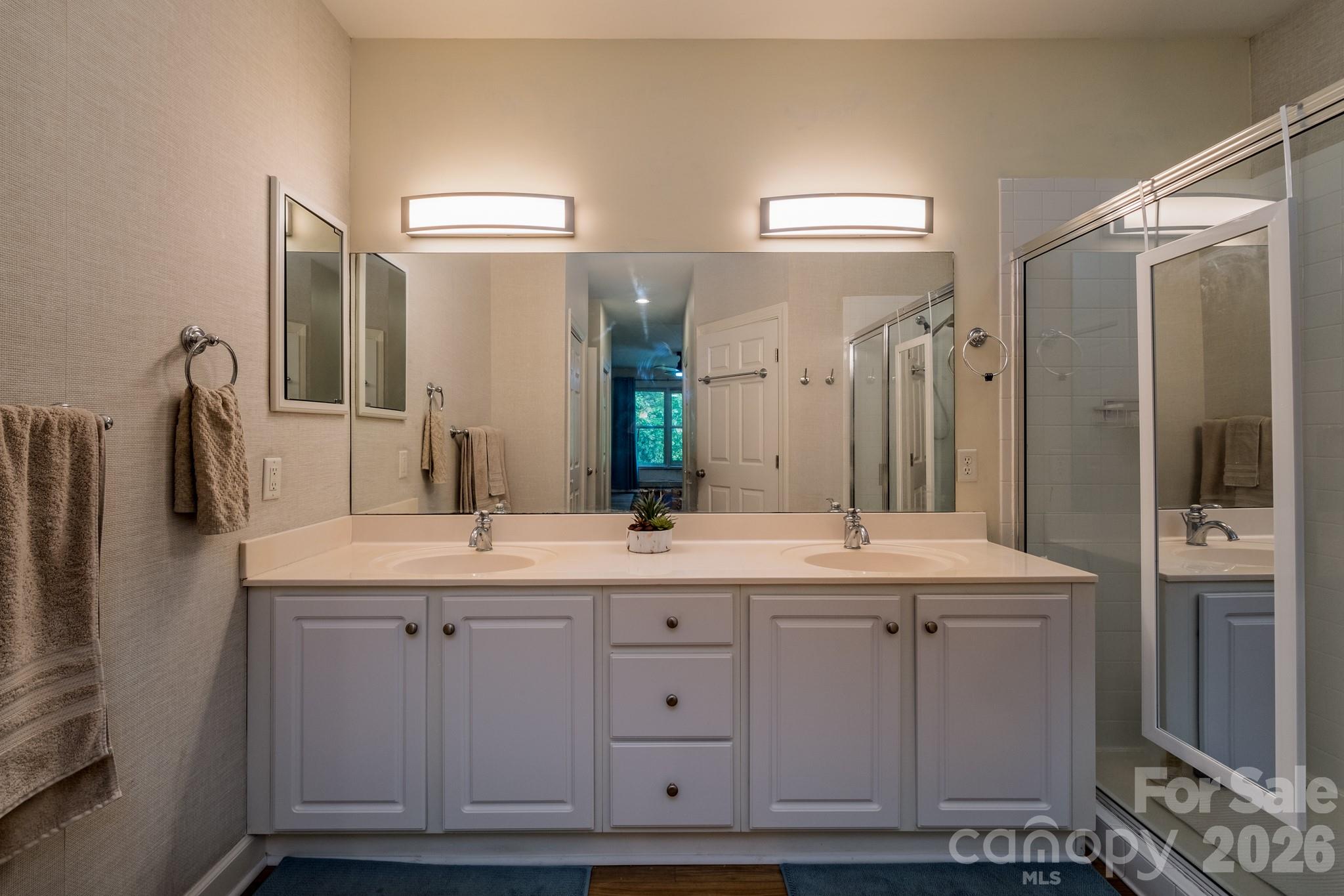 Dual Vanity Primary Bath – Expansive en-suite bathroom with double vanity, generous counter space, and bright lighting for added convenience. - 99 Ridgetop Circle, Brevard