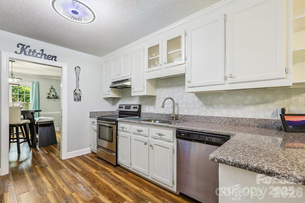 Renovated kitchen featuring crisp white cabinetry, granite countertops, and stainless steel appliances for a clean, modern look. - 806 Colony Oaks Drive, Monroe