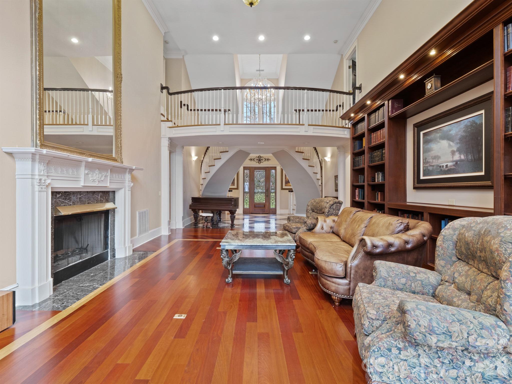 Soaring two stories high, the great room is adorned with exquisite built-in cabinetry illuminated by gentle downlighting, Brazilian Cherry floors framed with a contrasting inset, and a welcoming fireplace. - 1090 N Saunders Drive, Catawba