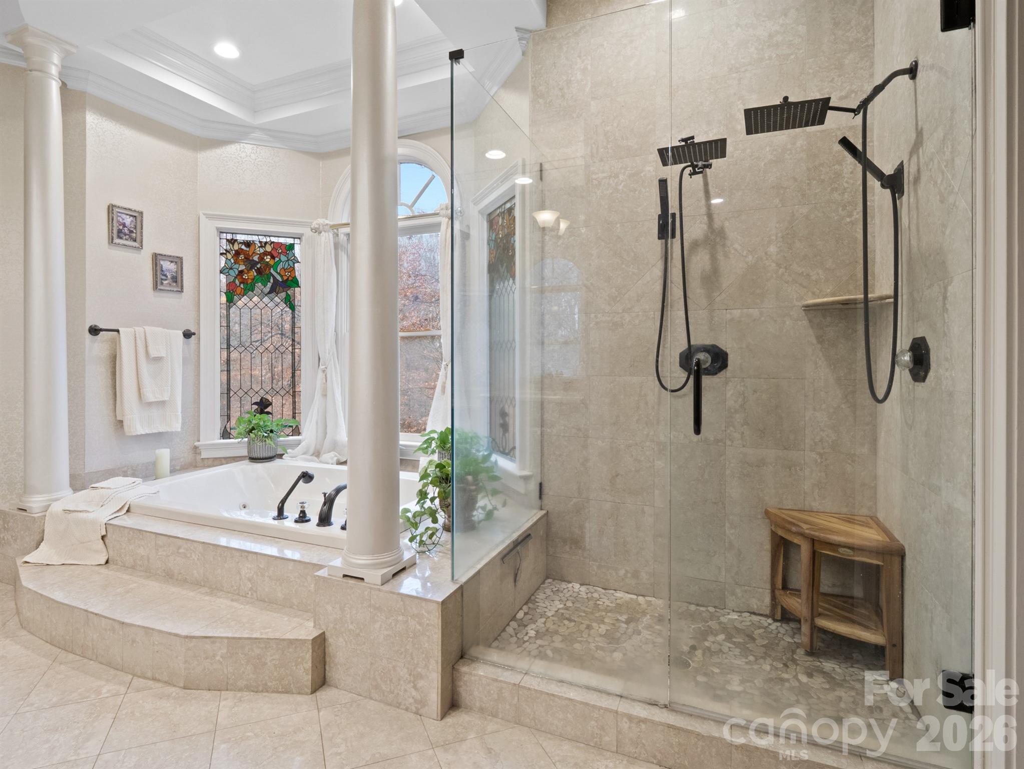 In the primary bath, you’ll find a spacious tile shower with dual heads, a soaking tub accented by graceful columns, and a double vanity with custom cabinets. - 1090 N Saunders Drive, Catawba