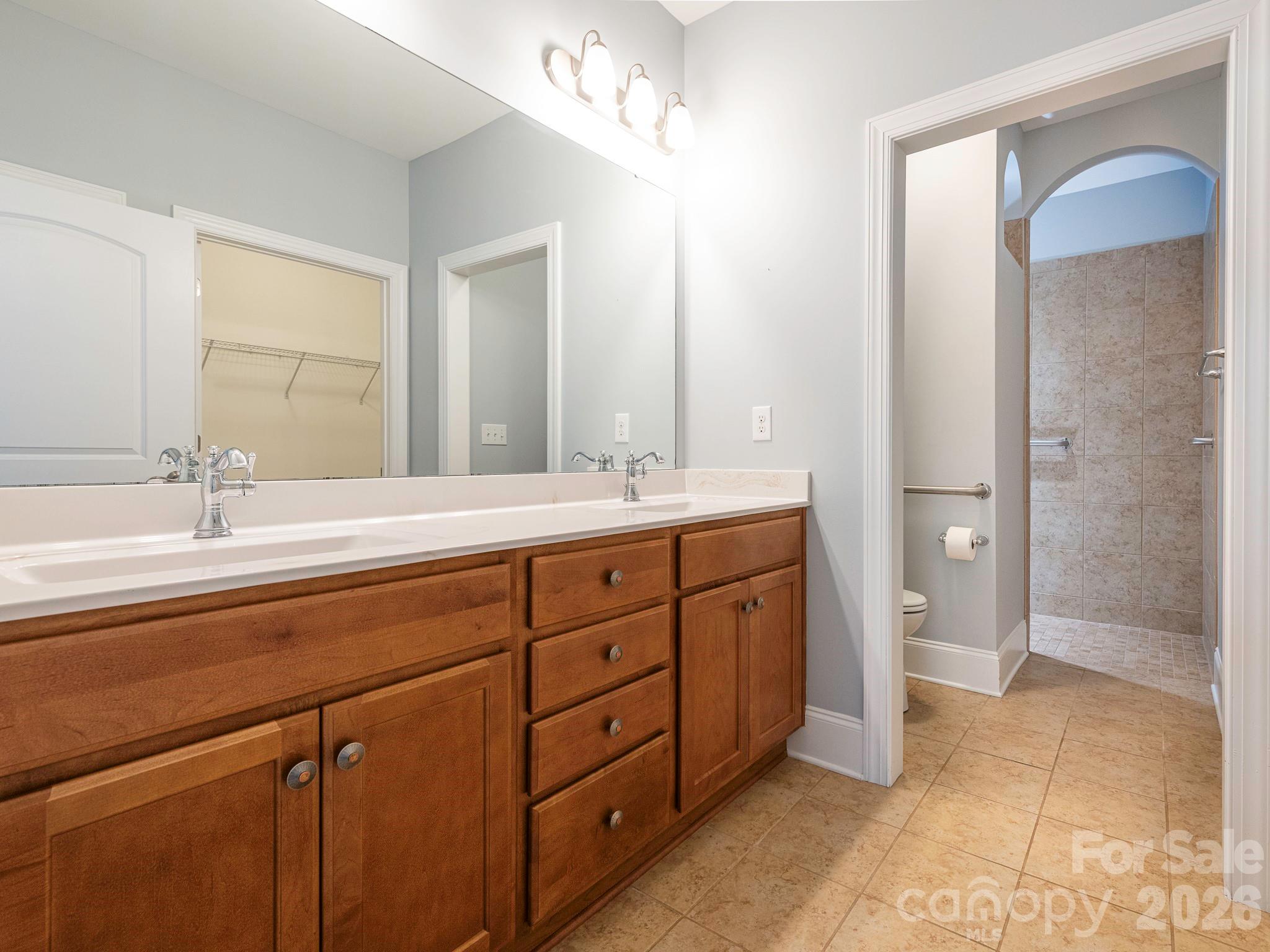 Adjoining primary bath with double sink vanity, linen closet and zero entry tile shower with grab bars - 4534 Ideal Way, Harrisburg