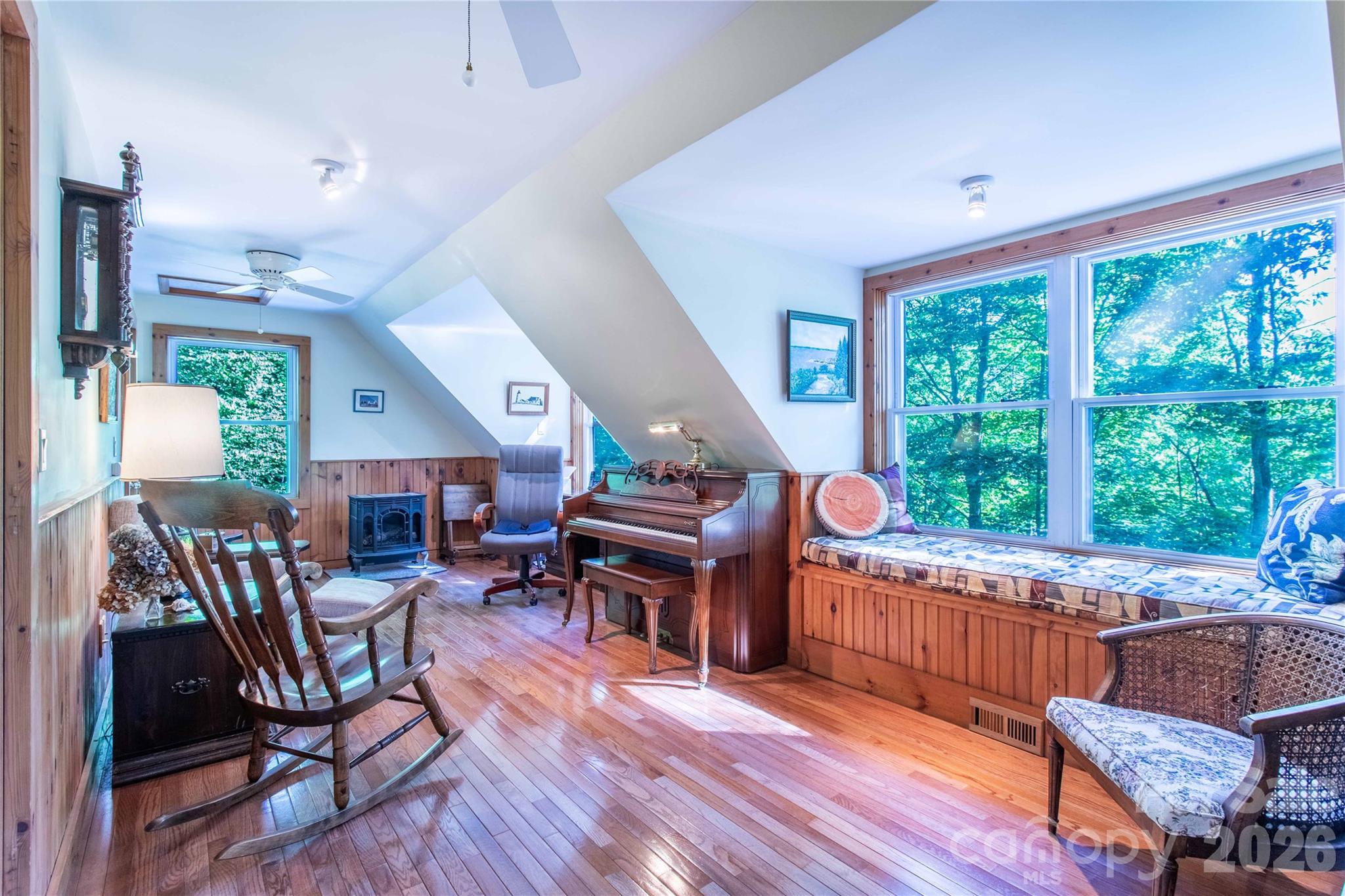 Sunny den/office room with built in bench seating. A full bathroom with a skylight is right to the left of this picture. Note the gas log stove for chilly days and nights. A laundry room is also off this main-level room, great for multigenerational living. - 22 Great Aspen Way, Black Mountain