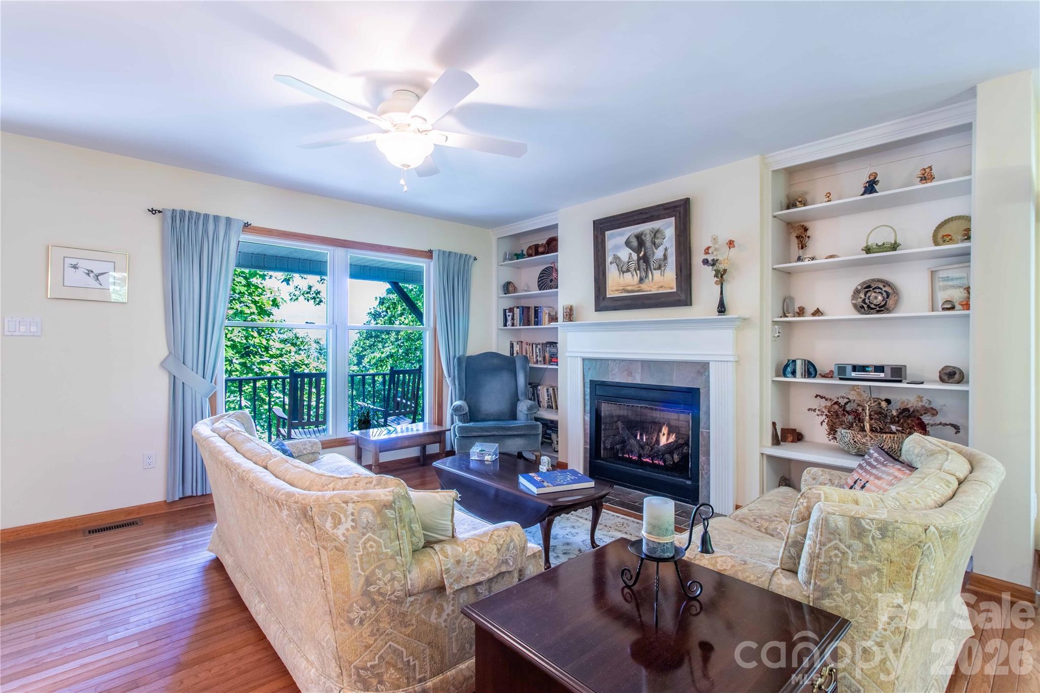 Living room with a mountain view, built in shelves, gas log fireplace, and gleaming wood floors. - 22 Great Aspen Way, Black Mountain