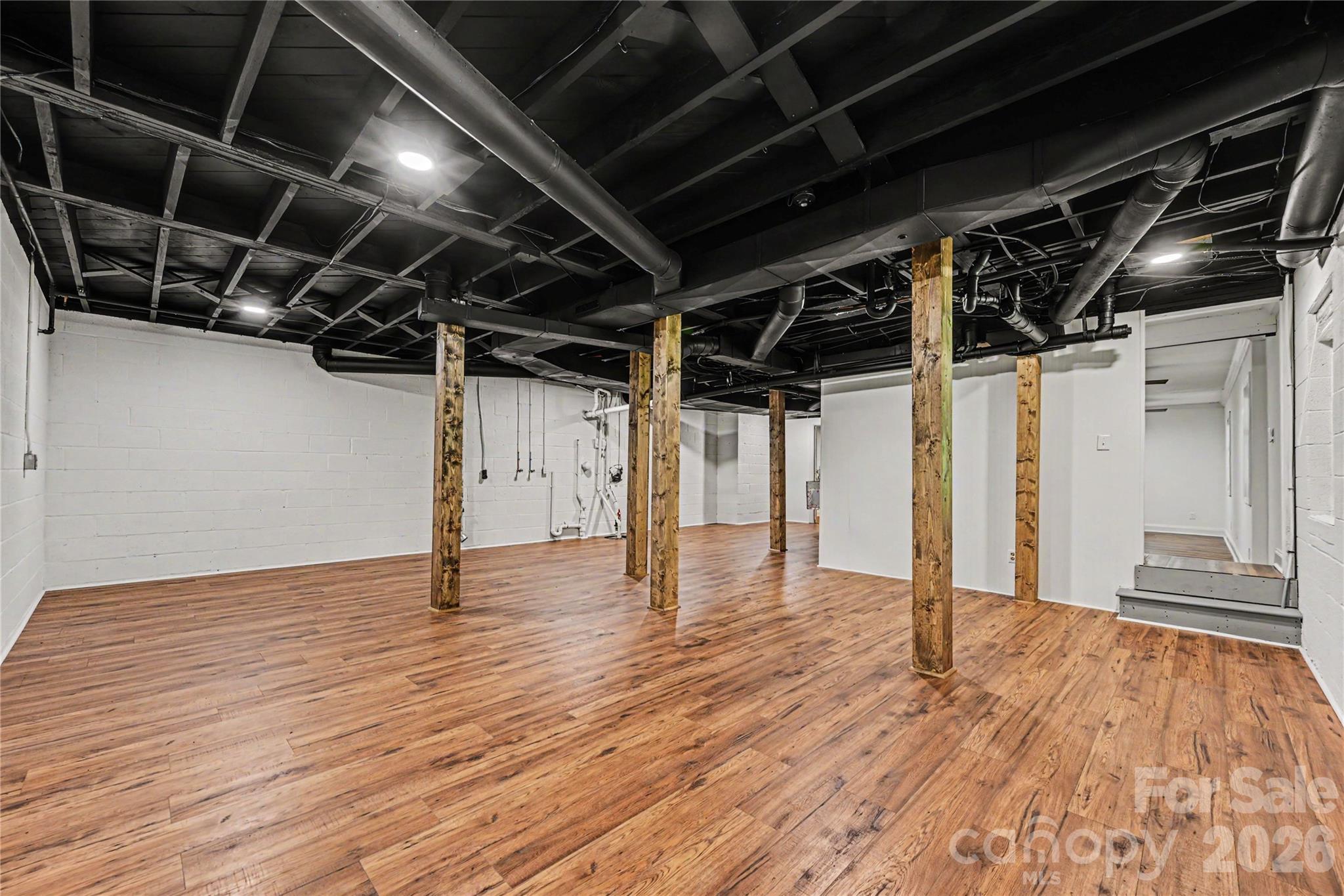 Basement Flex Space - Extensive lower level space featuring LVP flooring, wrapped columns, and room for recreation, fitness, hobbies, storage, or entertaining. - 716 Grandview Drive NE, Concord