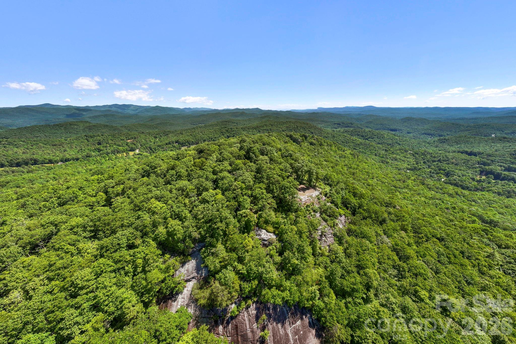 Aerial perspective showcases the unique position of the homesite atop a dramatic ridgeline with panoramic mountain views in multiple directions. - 9999 Rocky Mountain Road, Lake Toxaway