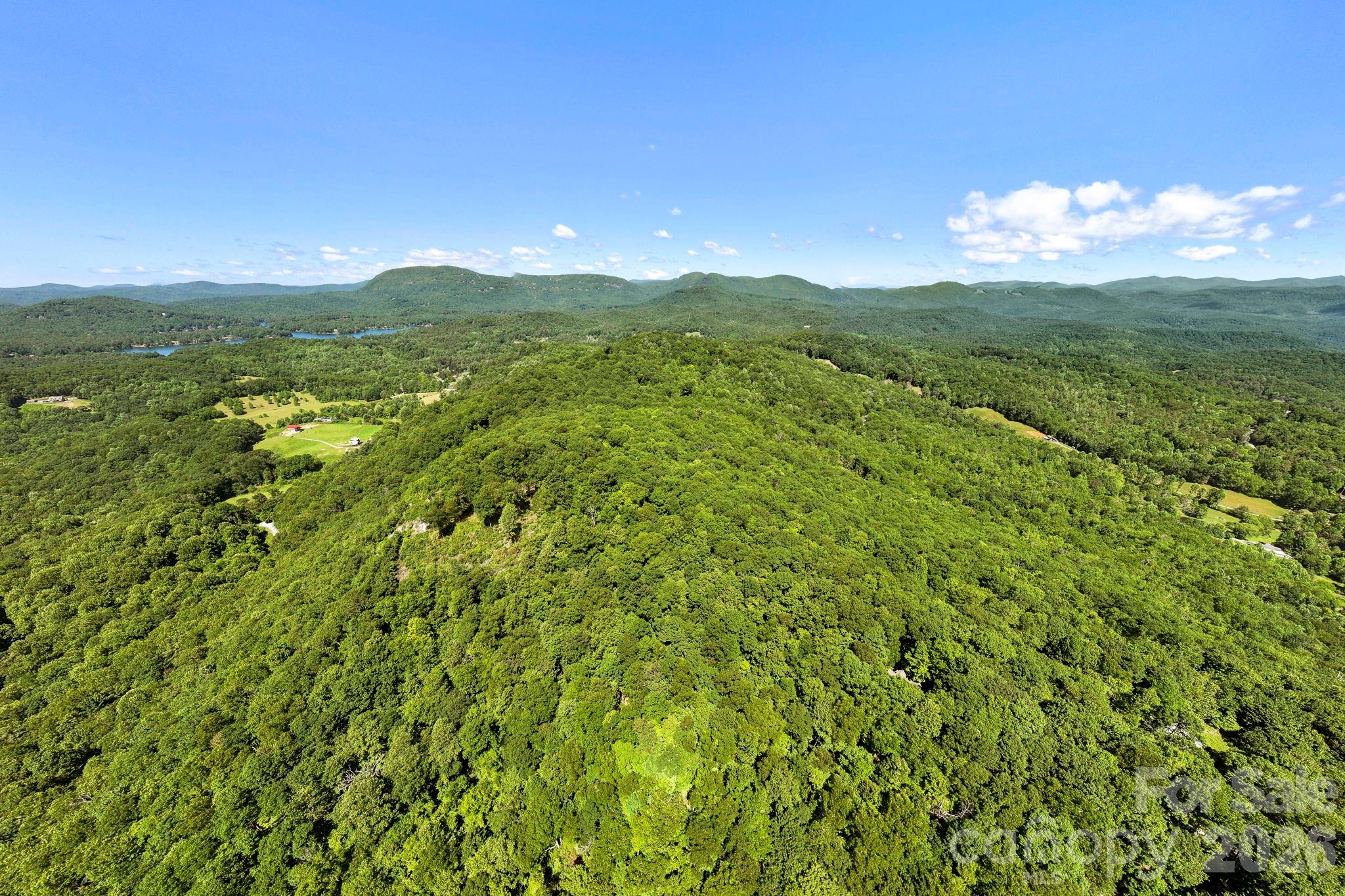 Sweeping drone views reveal the property's connection to the surrounding valleys, forests, and mountain ridges. - 9999 Rocky Mountain Road, Lake Toxaway