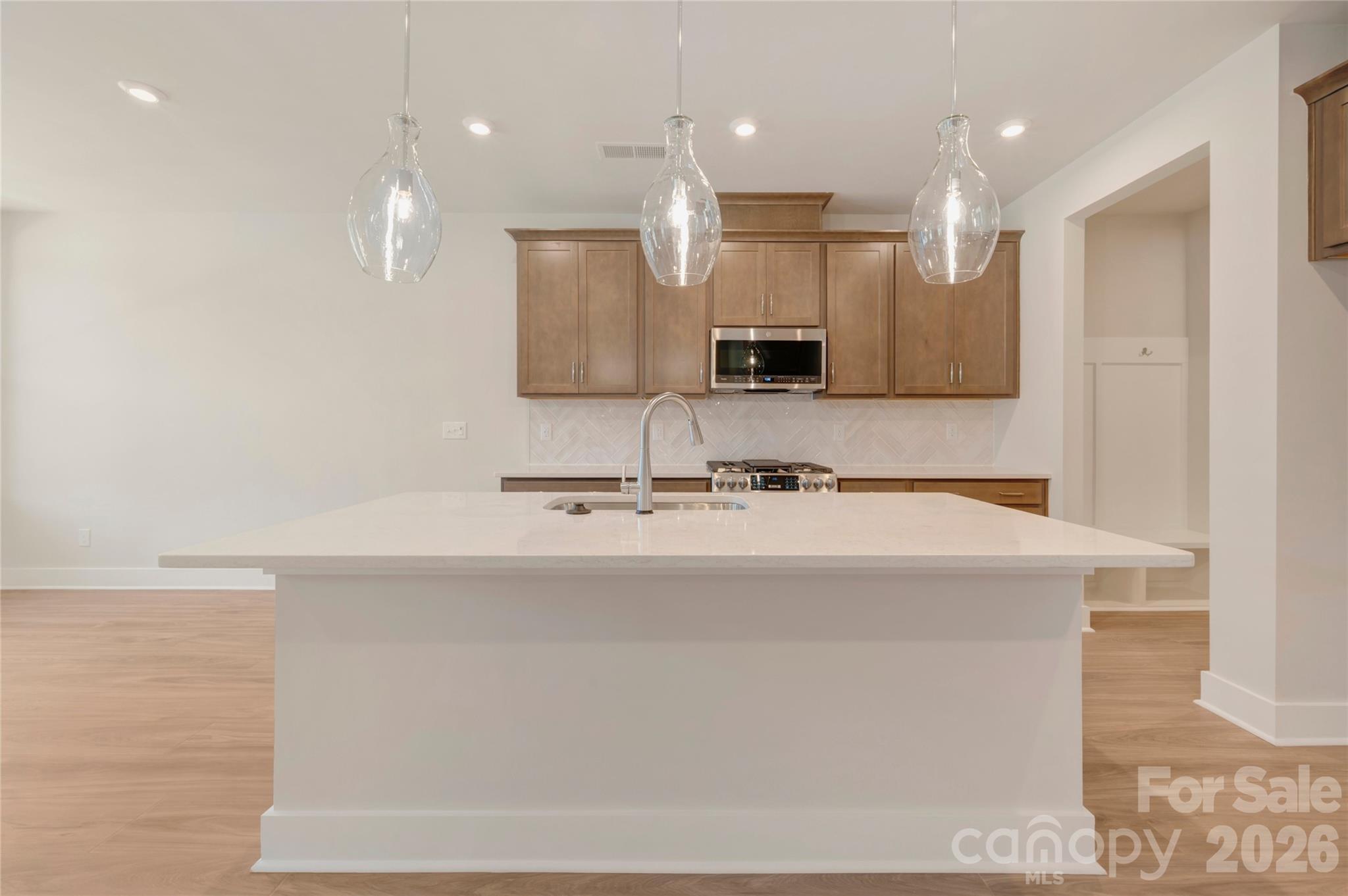 Chef inspired kitchen with warm brown cabinets paired with white quartz countertops - 316 Ardmore Drive, Belmont