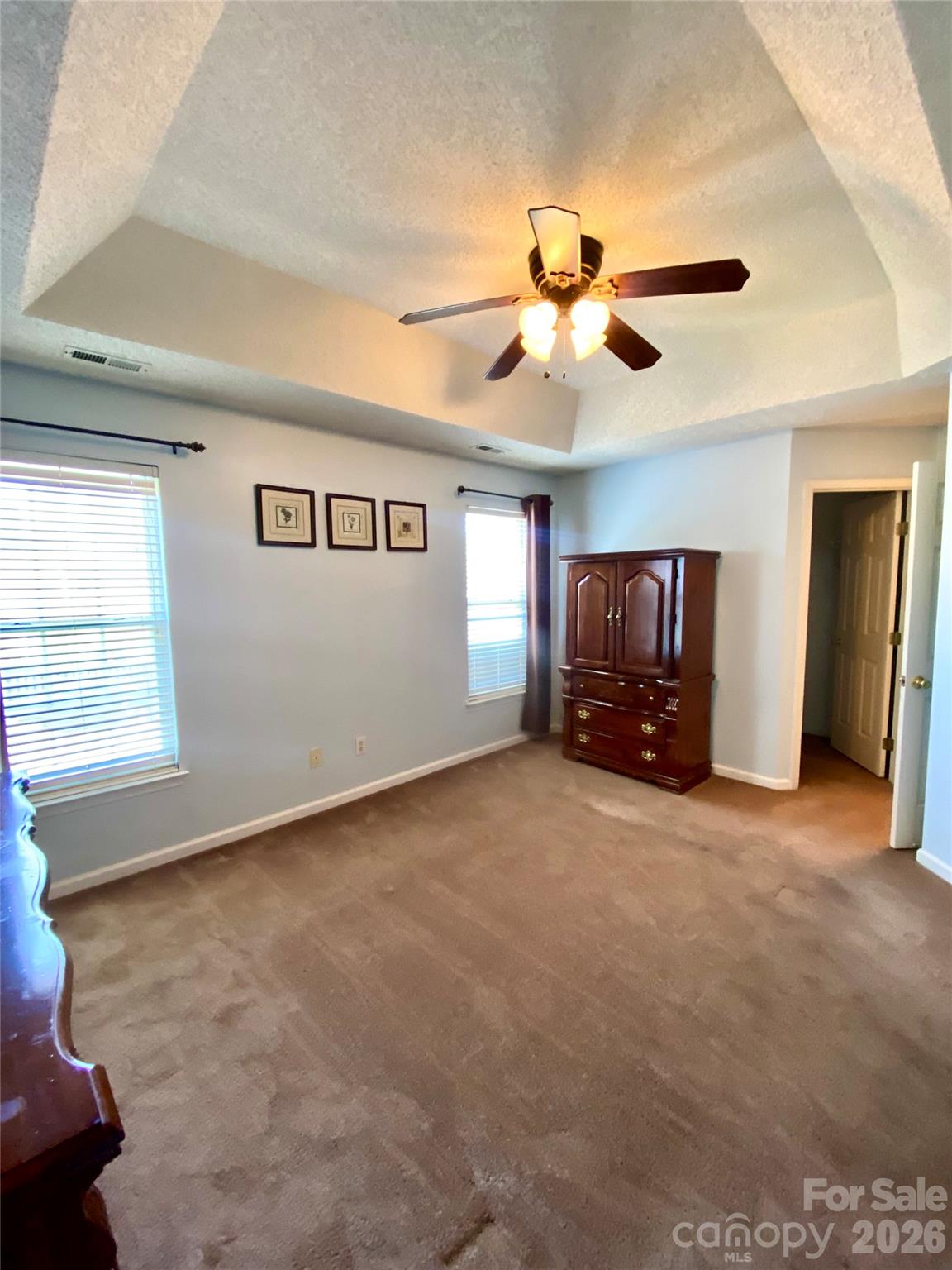 Primary Bedroom with tray ceiling and ceiling light/fan. - 6025 Creft Circle, Indian Trail