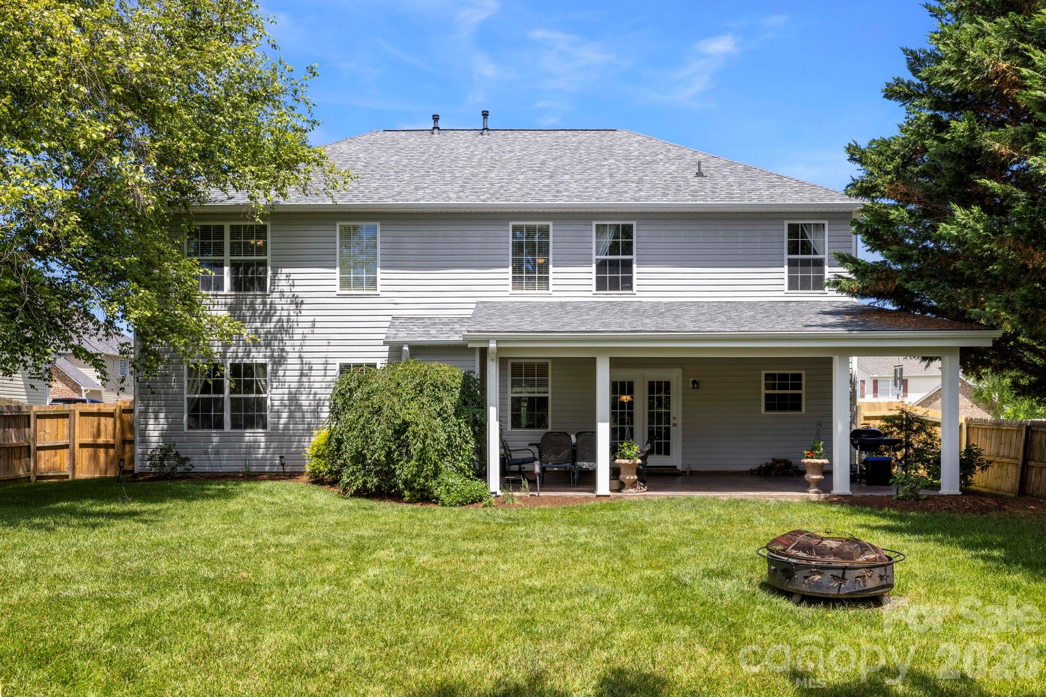 Fully fenced backyard featuring a large lawn and covered patio, offering plenty of room for outdoor activities and gatherings. - 266 Wildbriar Road, Fletcher