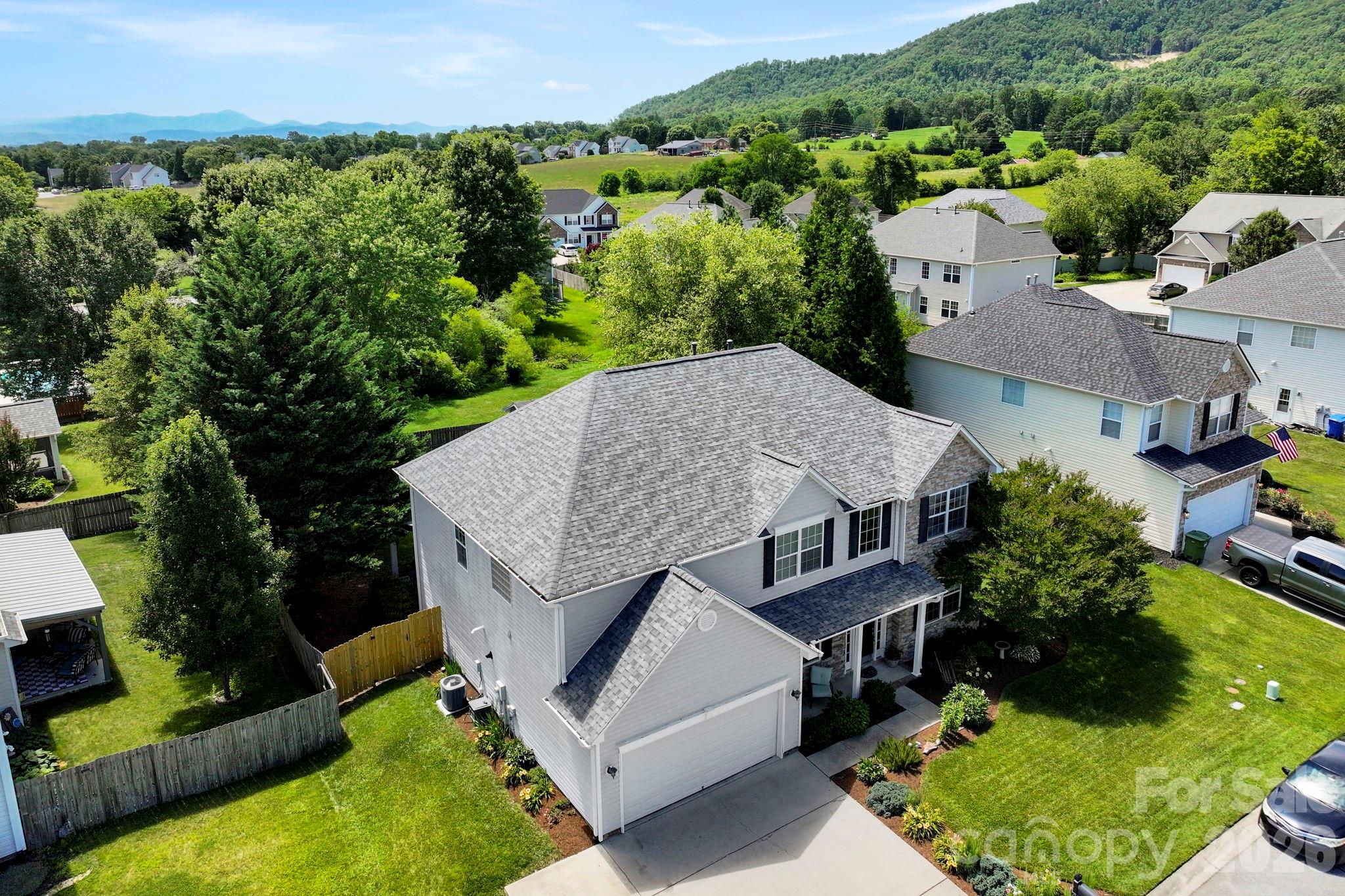 Elevated aerial view showcasing the home’s attractive curb appeal, landscaped lot, and surrounding mountain backdrop. - 266 Wildbriar Road, Fletcher