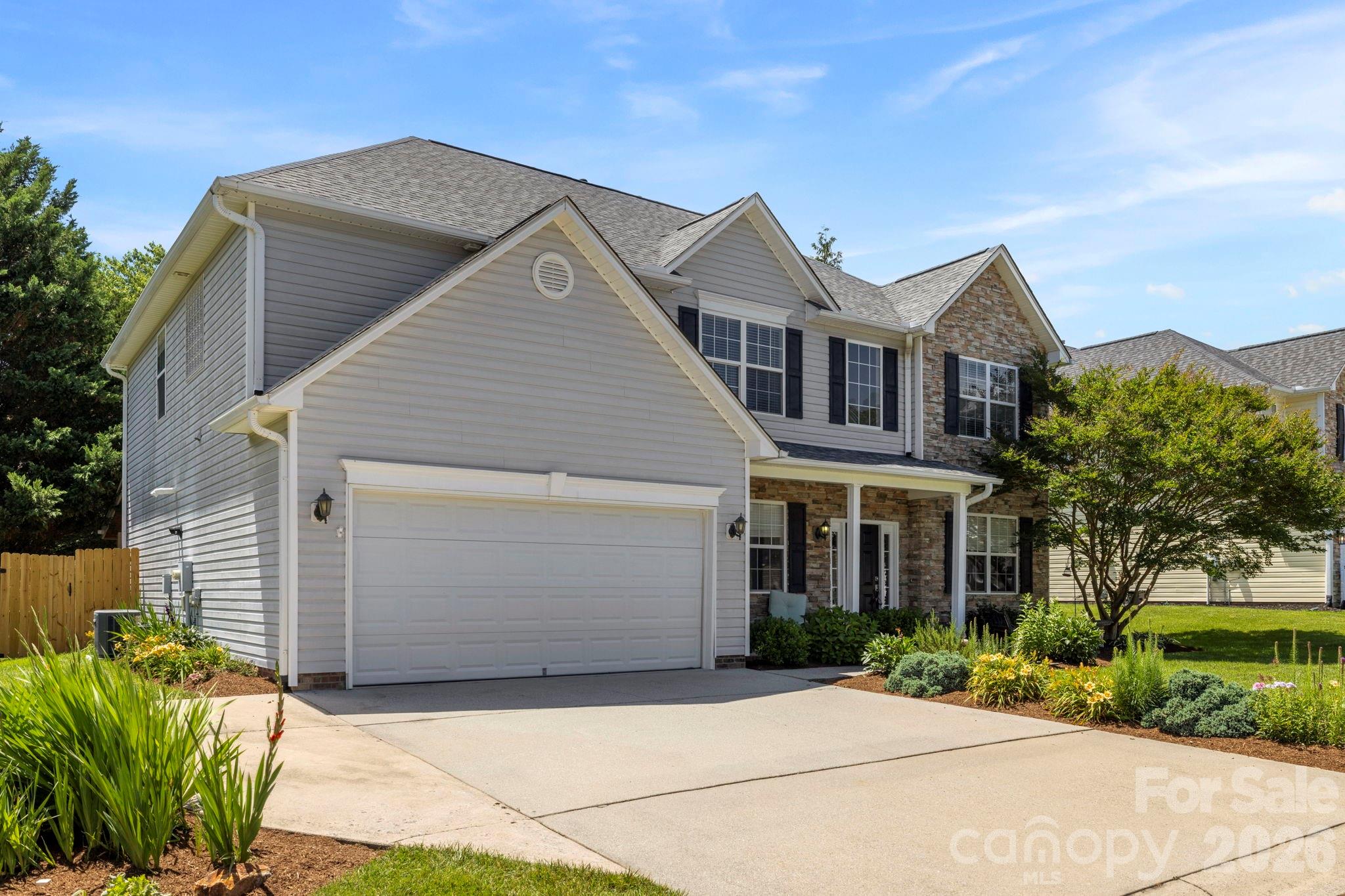 Spacious driveway leading to a two-car garage, complemented by mature landscaping and charming architectural details. - 266 Wildbriar Road, Fletcher