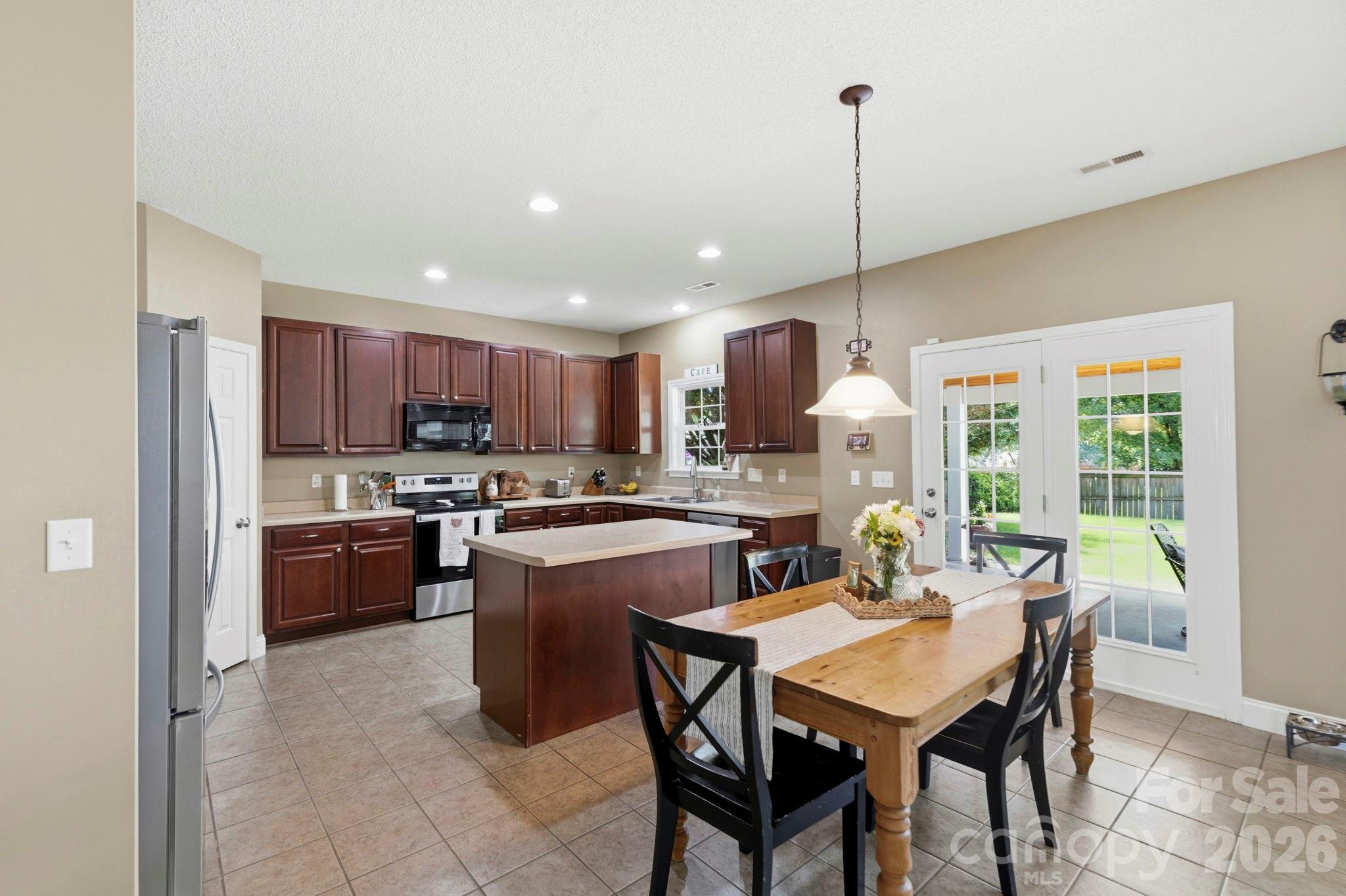 Spacious eat-in kitchen featuring abundant cabinetry, center island, recessed lighting, and backyard access. - 266 Wildbriar Road, Fletcher