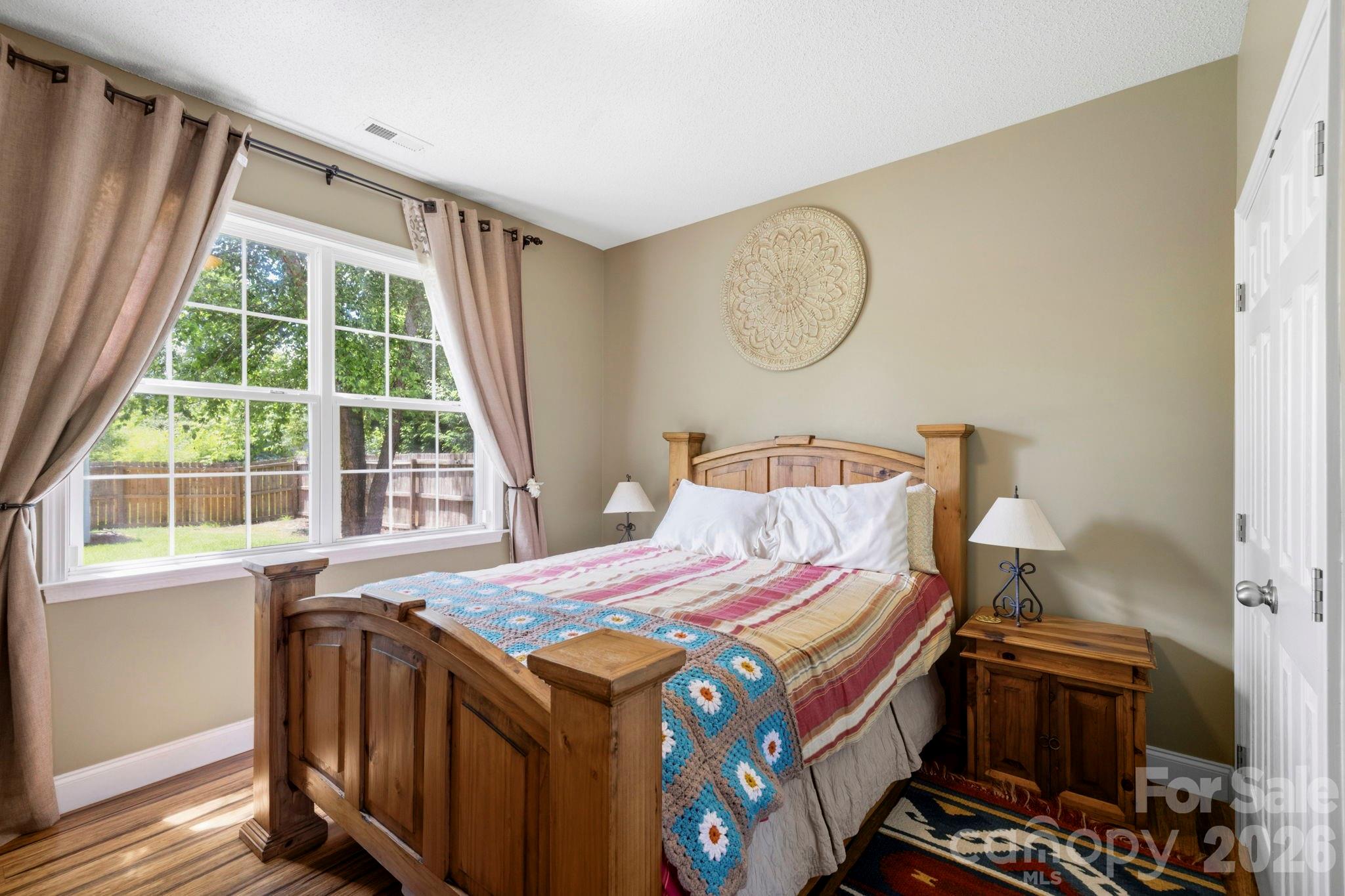 Comfortable main-level bedroom featuring large windows, abundant natural light, and peaceful backyard views. - 266 Wildbriar Road, Fletcher