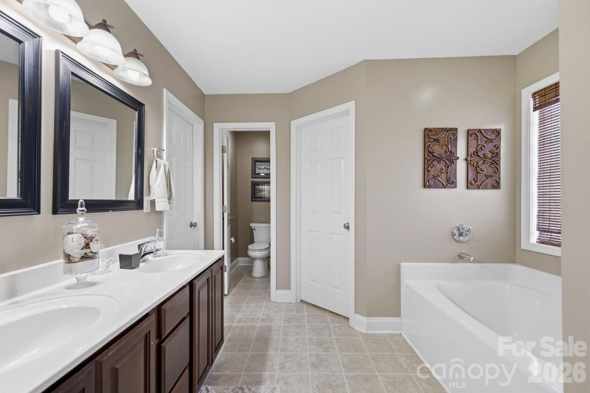 Well-appointed primary bath offering dual vanities, a soaking tub, private water closet, and abundant storage for everyday convenience. - 266 Wildbriar Road, Fletcher