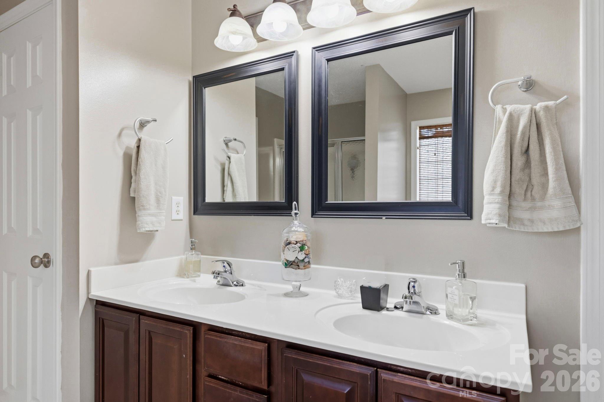 Spacious double-sink vanity with framed mirrors, ample counter space, and functional storage cabinetry in the primary bathroom. - 266 Wildbriar Road, Fletcher