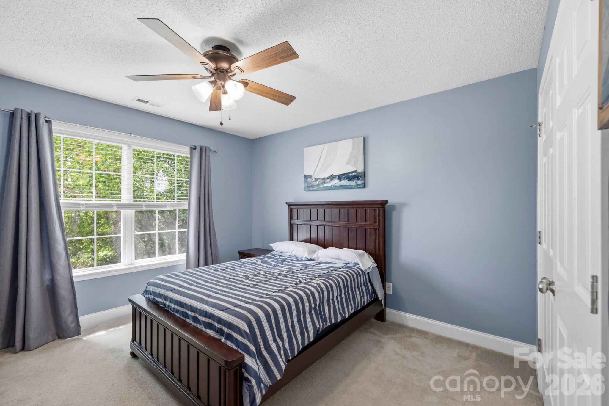 Comfortable bedroom with soothing color palette, abundant natural light, and wooded views through oversized windows. - 266 Wildbriar Road, Fletcher