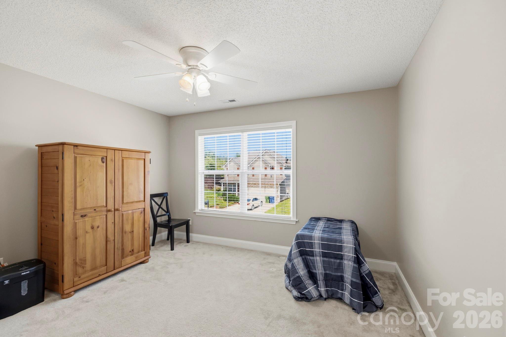 Bright and spacious secondary bedroom featuring plush carpeting, a large window, and neutral finishes ready for personalization. - 266 Wildbriar Road, Fletcher