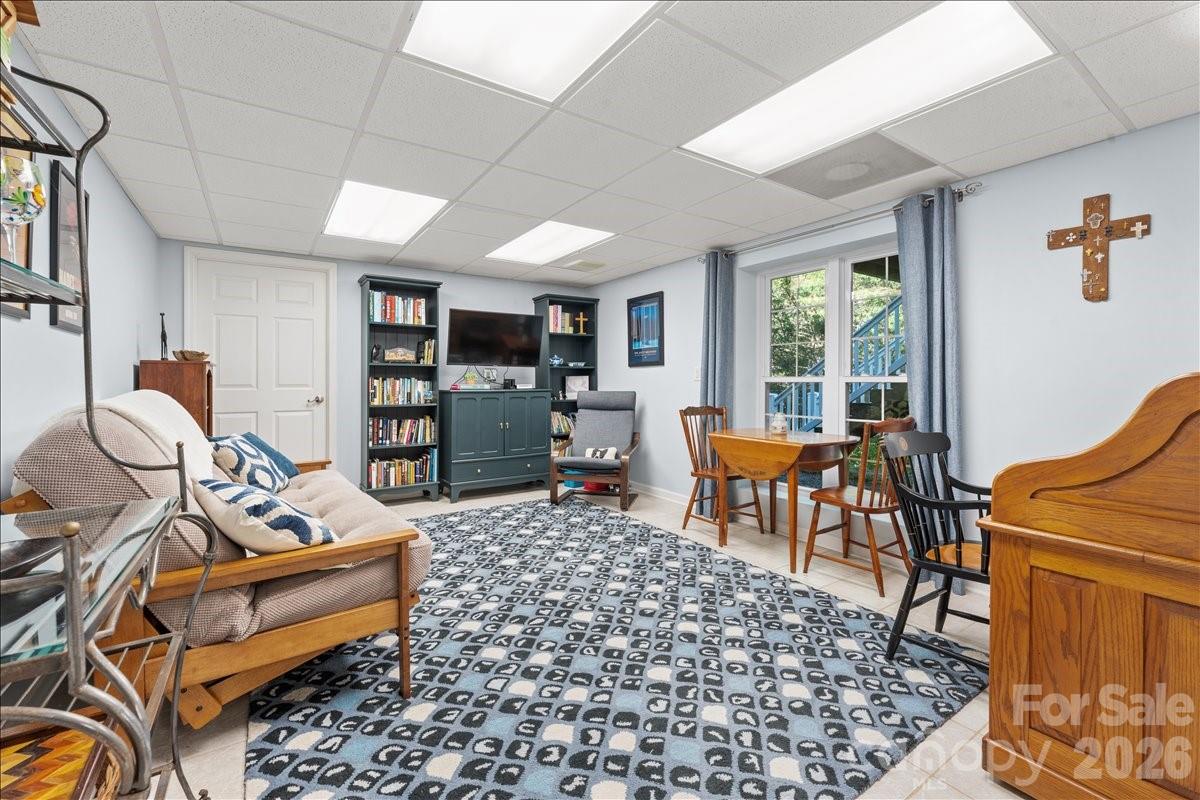 The downstair living space also has tiled floors as well as large windows .  The door to the far side of the pictures leads to a storage room. - 104 Balsam Circle, Troy