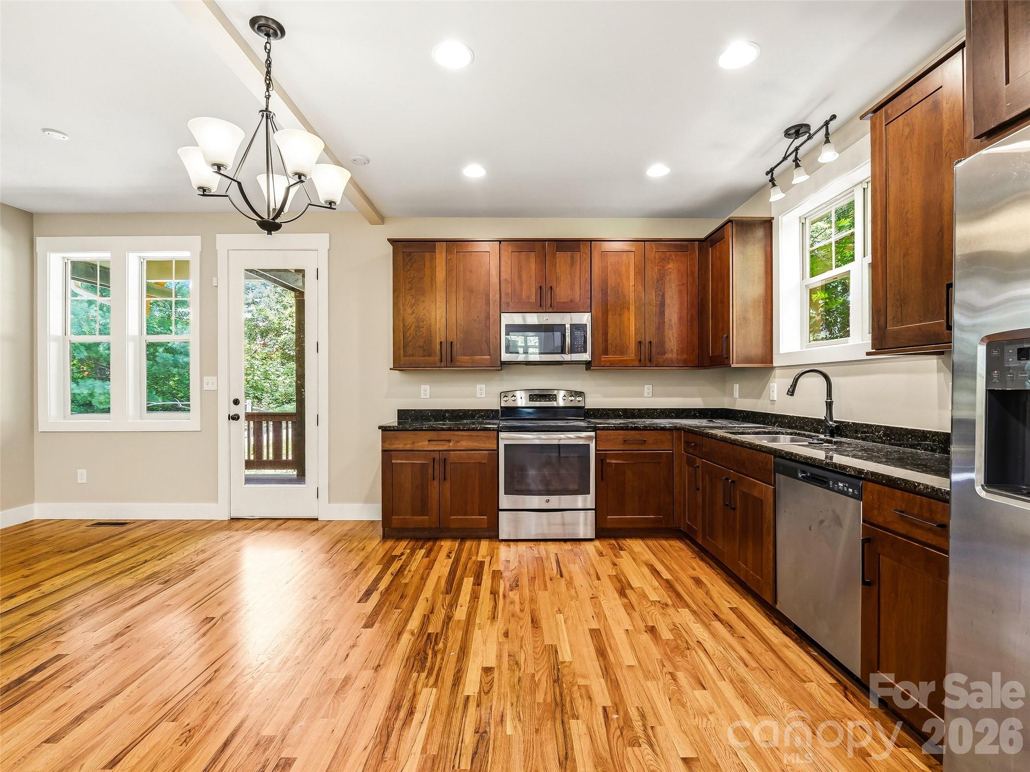 Modern kitchen equipped with stainless steel appliances, ample cabinetry, and wood floors. - 25 Shady Park Lane, Asheville