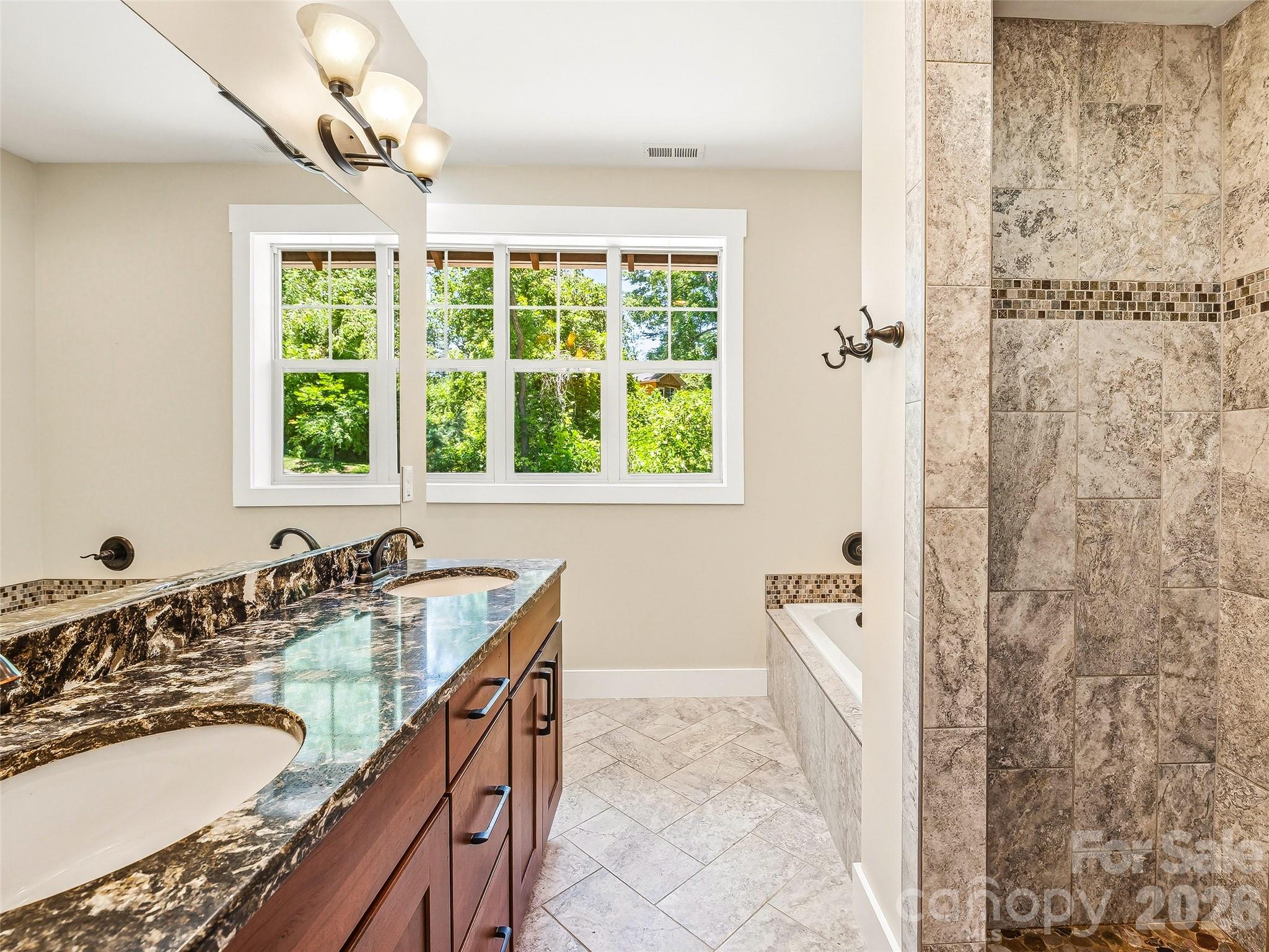 Primary bathroom suite complete with a dual-sink vanity and a relaxing garden tub. - 25 Shady Park Lane, Asheville