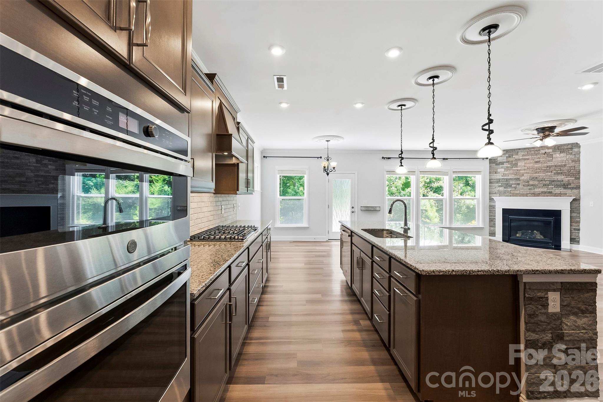 Upgraded, sleek and stylish this Chefs Gourmet Kitchen is sure to delight and make a wonderful location to entertain guests. Built in Microwave/oven, gas cooktop, large chefs island with sink, granite countertops and tile backsplash, upgraded lighting, upgraded vent hood. - 1318 Poppy Way, Matthews