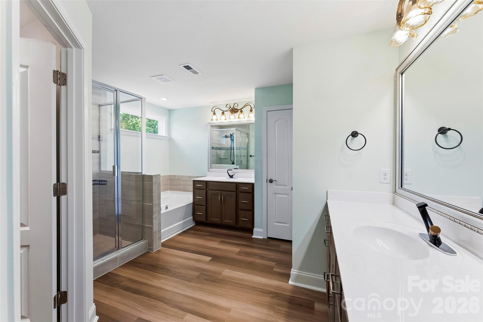 Primary Bathroom has standing glass shower, garden tub, dual vanities, upgraded vanities and faucets, lighting and mirrors. Walk in Closet off of Primary Bathroom. - 1318 Poppy Way, Matthews