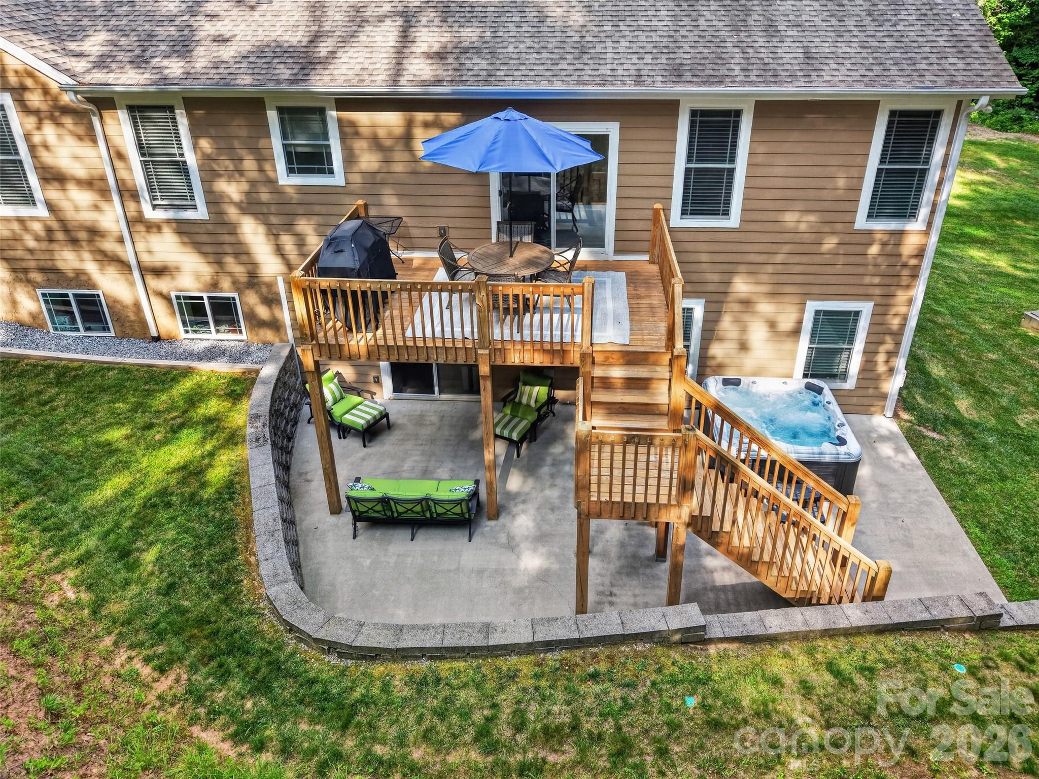 Spacious main-level deck designed for effortless grilling and outdoor entertaining, also a lower sitting area and hot tub to enjoy the surrounding natural setting - 290 Sweetwater Hills Drive, Hendersonville
