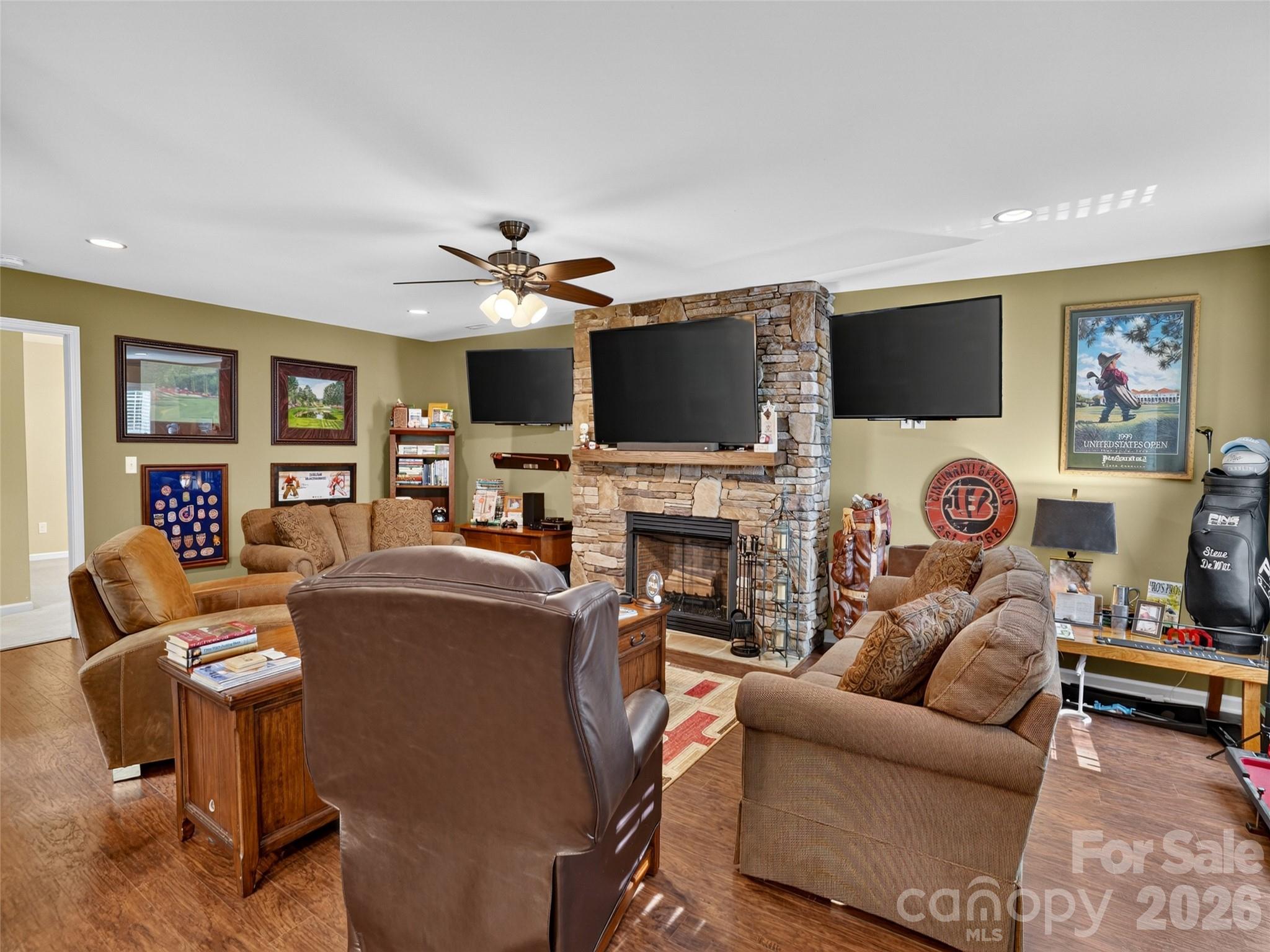 Expansive media room featuring three large-screen televisions, immersive surround sound, and a dramatic floor-to-ceiling stacked stonefireplace - 290 Sweetwater Hills Drive, Hendersonville