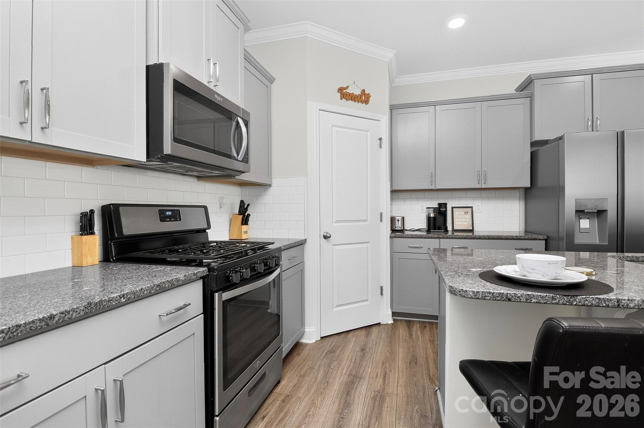 Chef's kitchen features gas range, huge island with breakfast bar, corner pantry, granite countertops, subway tile backsplash, abundant cabinetry - 1019 Chicory Trace, Clover