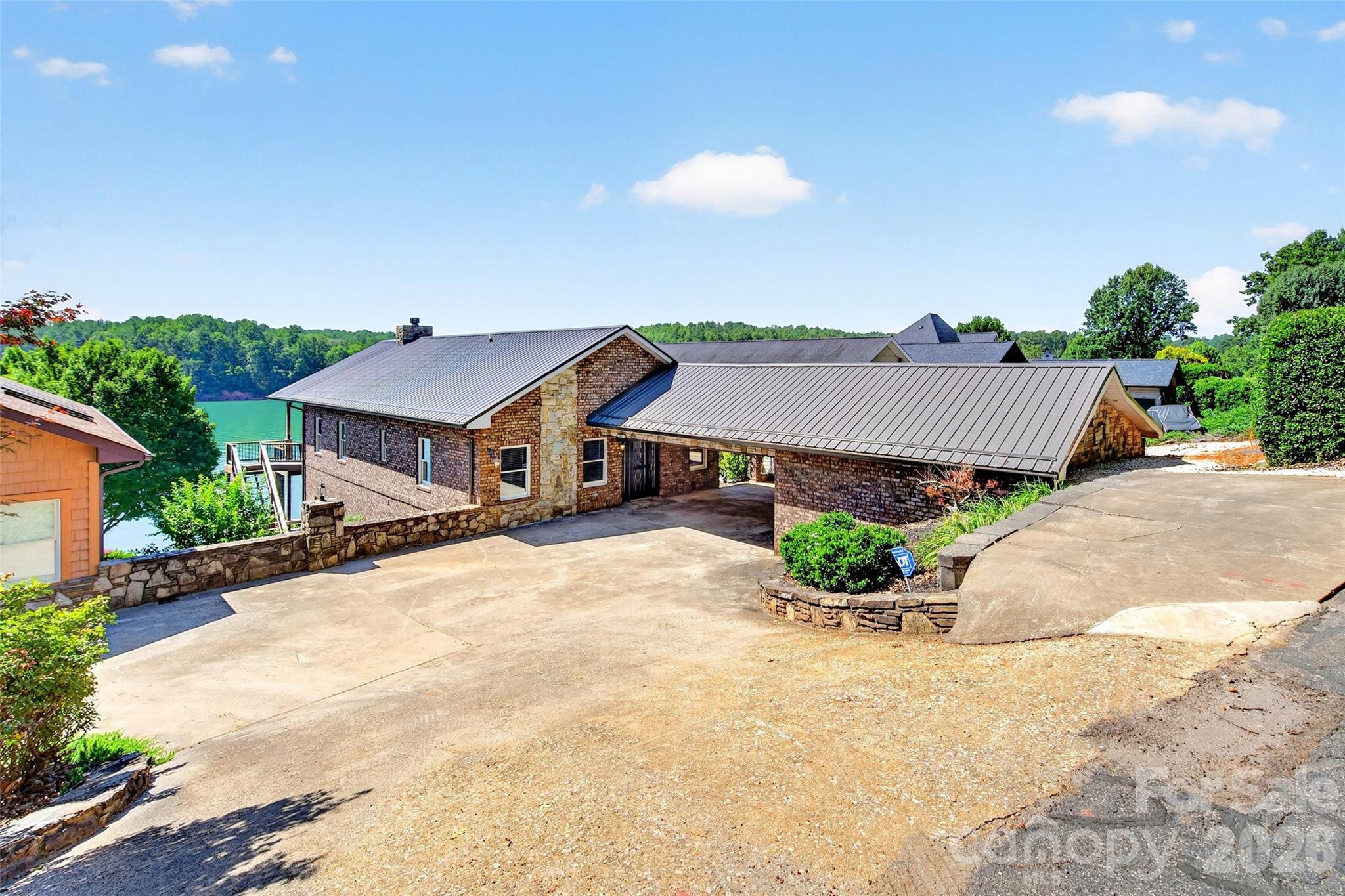 Street-side elevation with rock and brick exterior, attached two-space carport, and concrete driveway. - 831 Lake Club Drive, Nebo
