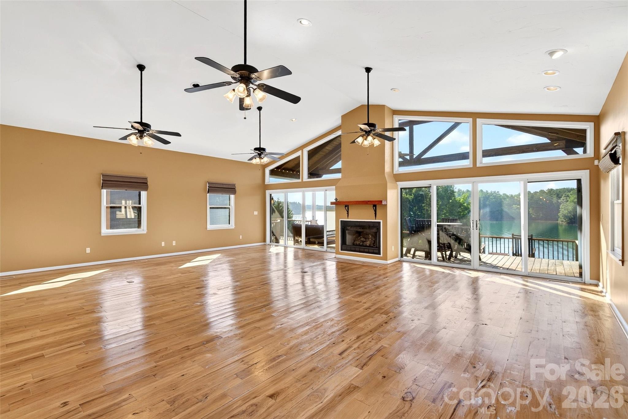 Living room glass wall framing Lake James, tinted to cut glare while keeping the year-round water view. - 831 Lake Club Drive, Nebo