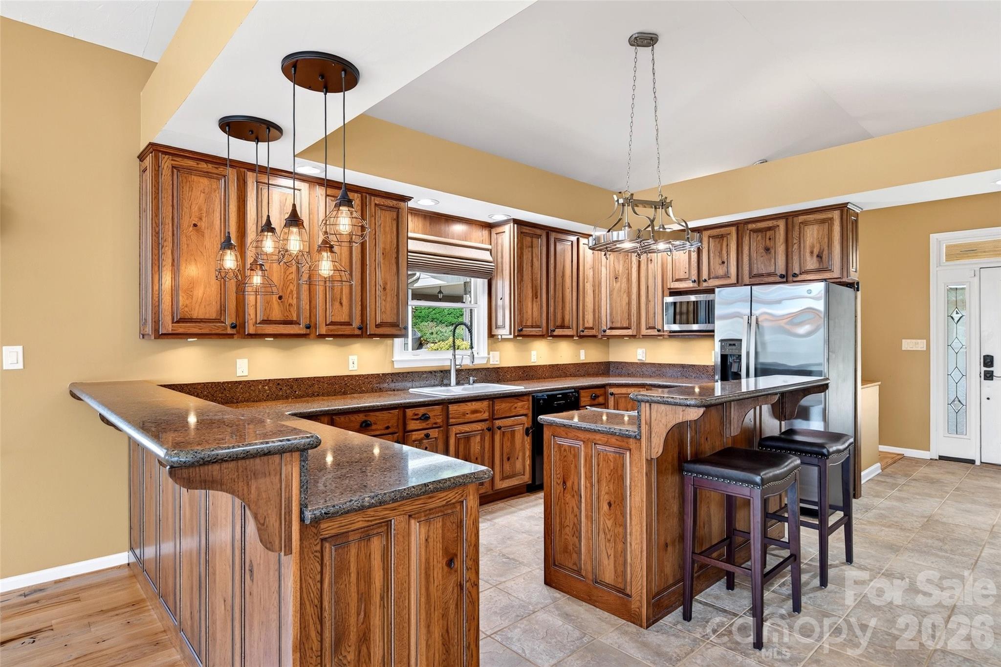 Kitchen with center island, custom hickory cabinetry, quartz counters, and pendant lighting. - 831 Lake Club Drive, Nebo