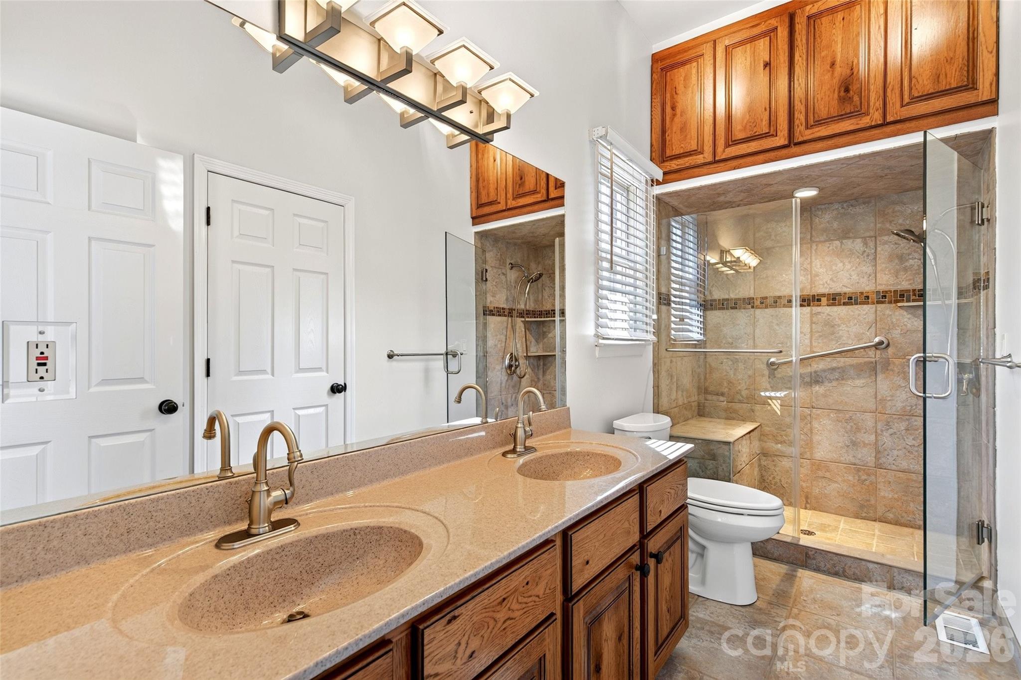 Main-level bath with wood vanity, framed mirror, and tile flooring. - 831 Lake Club Drive, Nebo