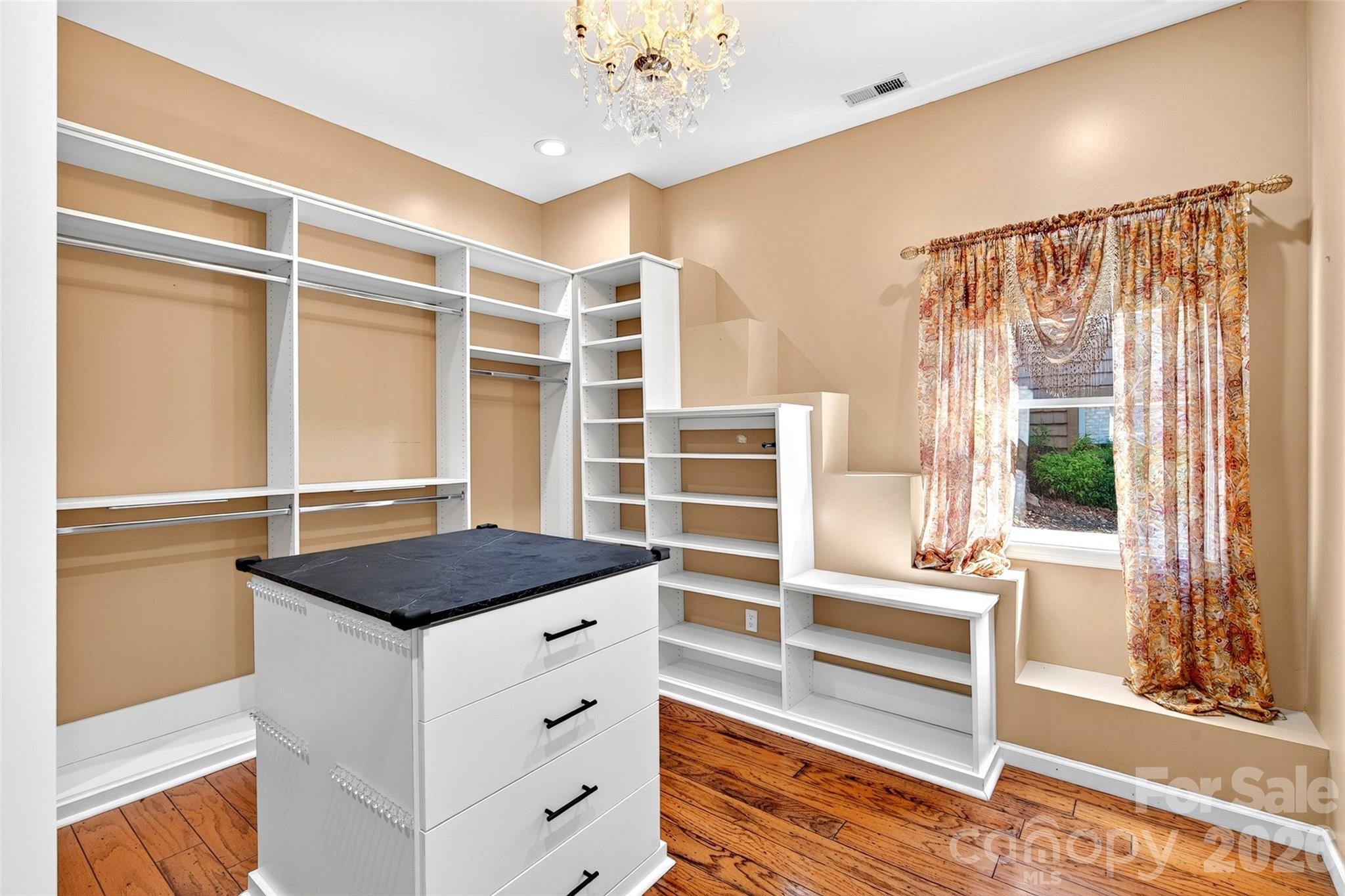Dressing room with full built-in shelving, a drawer island, and natural light. - 831 Lake Club Drive, Nebo