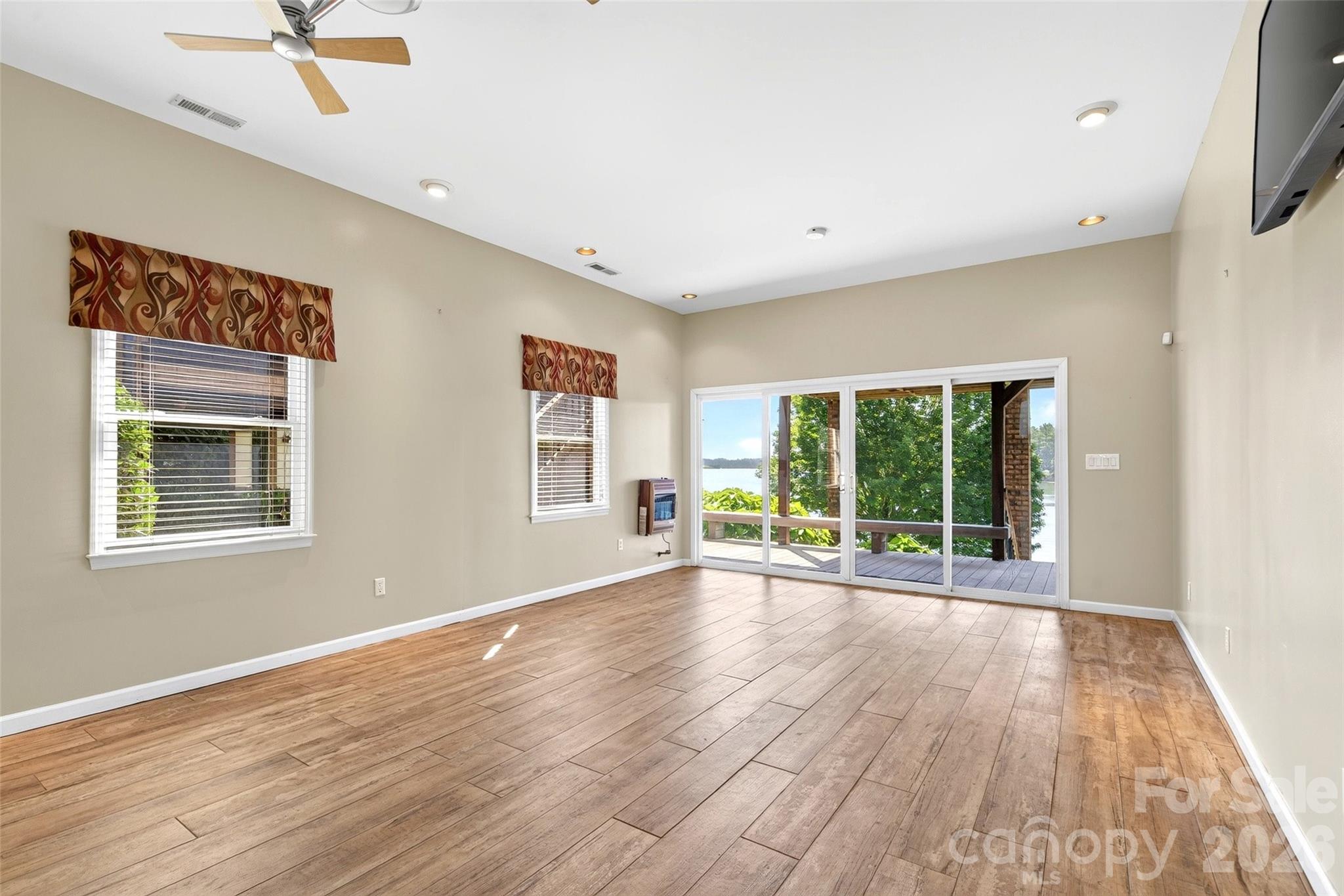 Main-level primary bedroom with hickory hardwood floors and windows to the lake side. - 831 Lake Club Drive, Nebo
