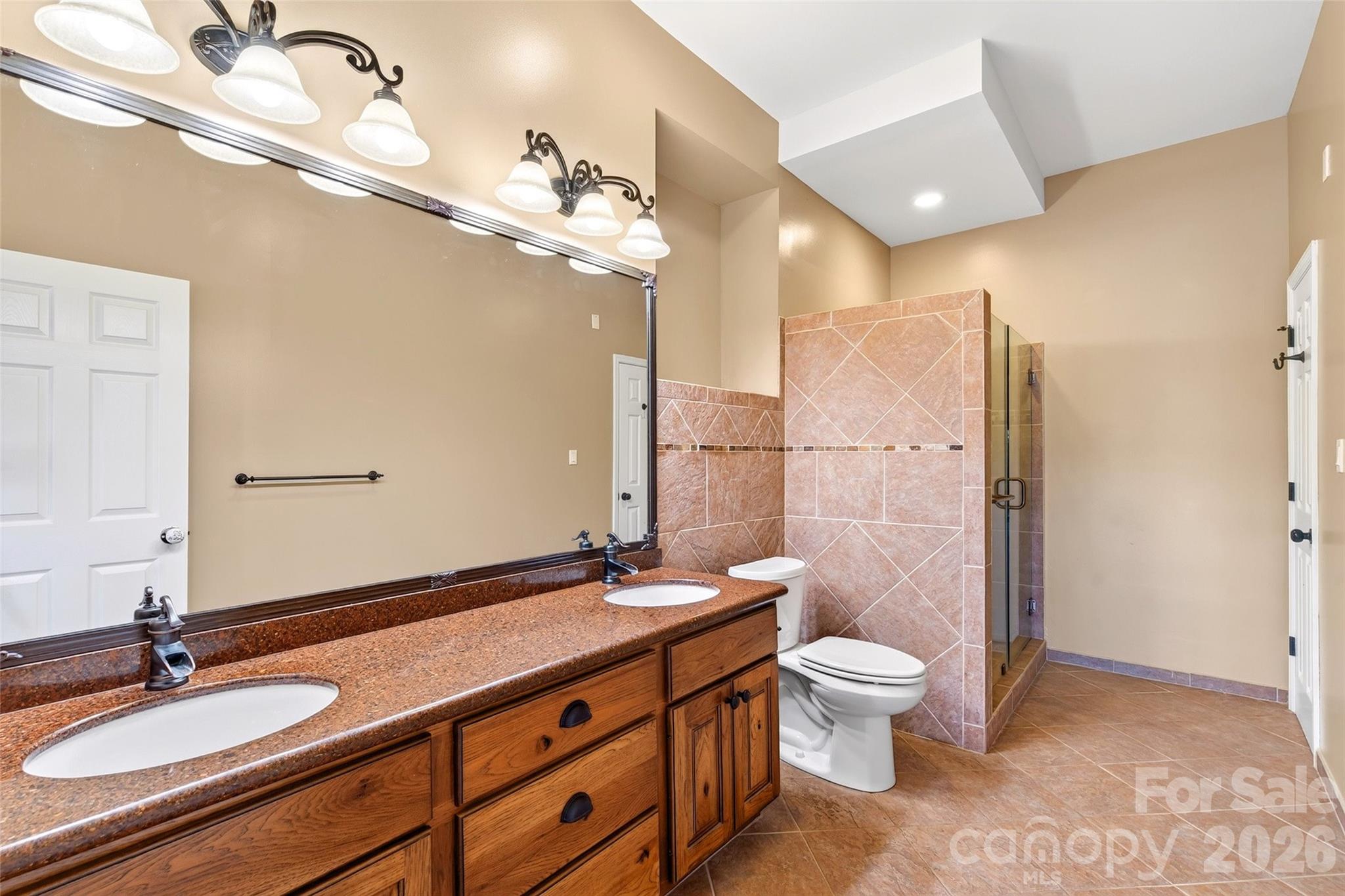 Lower-level bath with double vanity and full tile surround. - 831 Lake Club Drive, Nebo