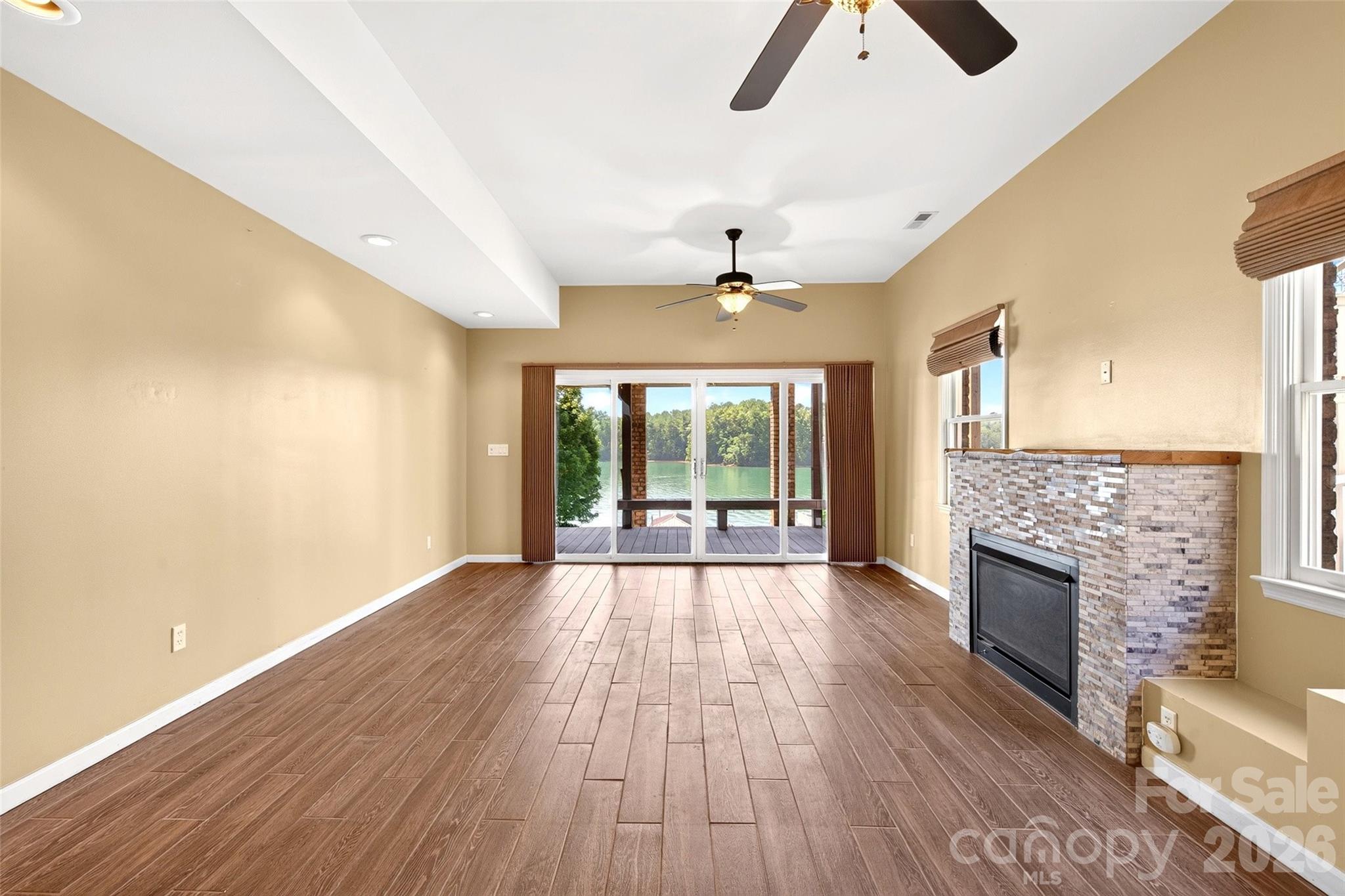 Lower-level suite with fireplace and sliding door opening toward the dock path. - 831 Lake Club Drive, Nebo
