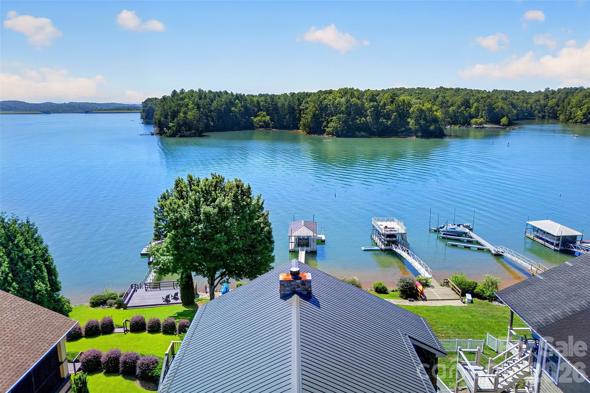 Aerial of 831 Lake Club Drive showing brown metal roofs, level lawn, and private dock on Lake James. - 831 Lake Club Drive, Nebo