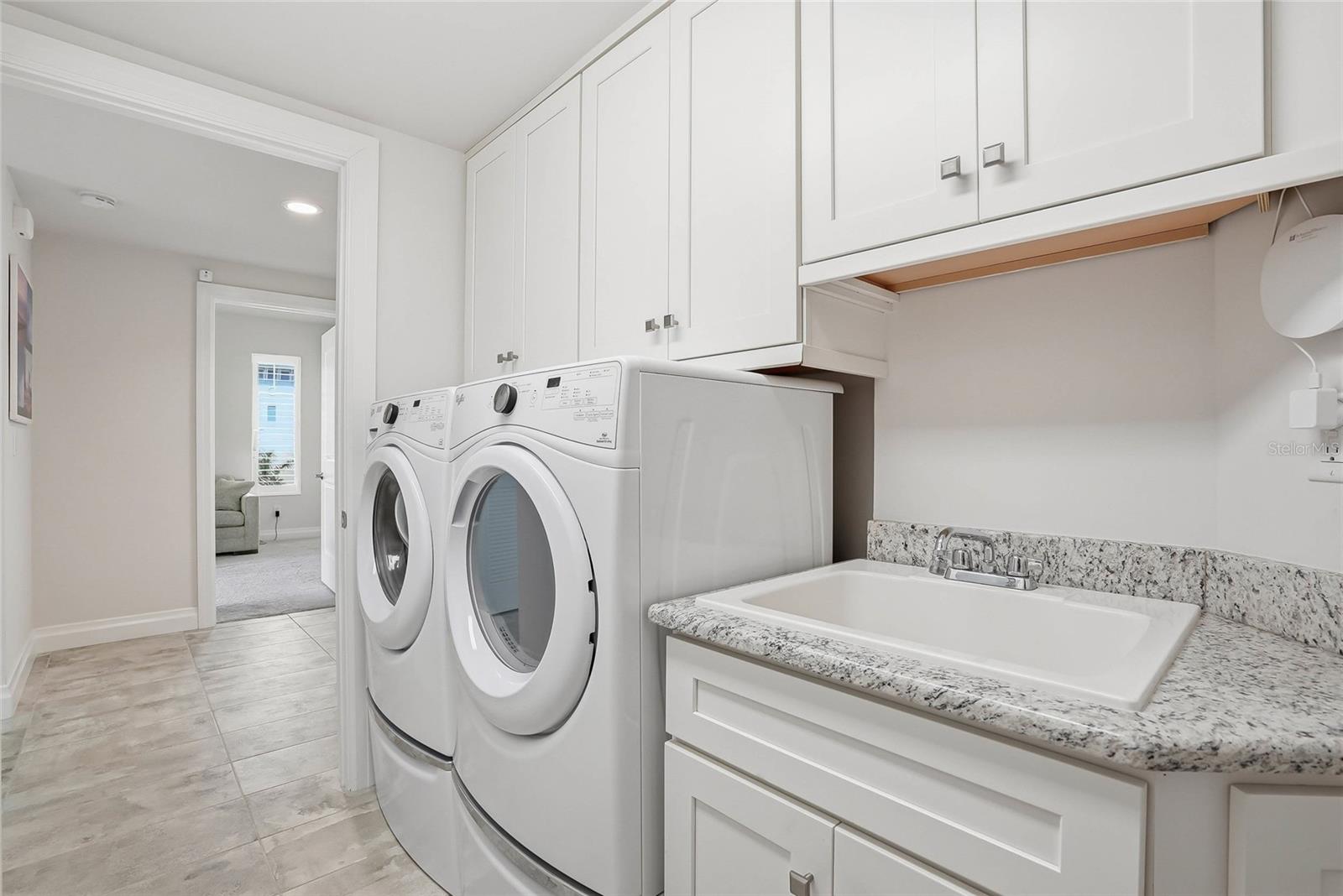 Laundry room with built-in cabinetry and utility sink. - 650 COLLANY RD #401, TIERRA VERDE
