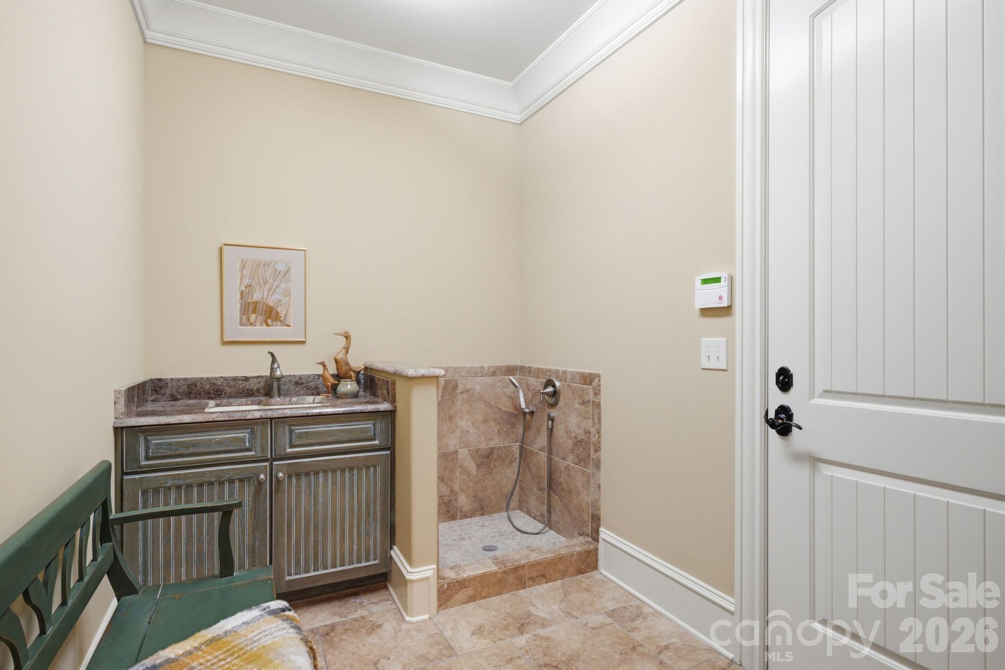 Mud room with cabinet and sink. Dog shower or muddy boot bath off lower level oversized garage - 8528 Waxhaw Creek Road, Waxhaw