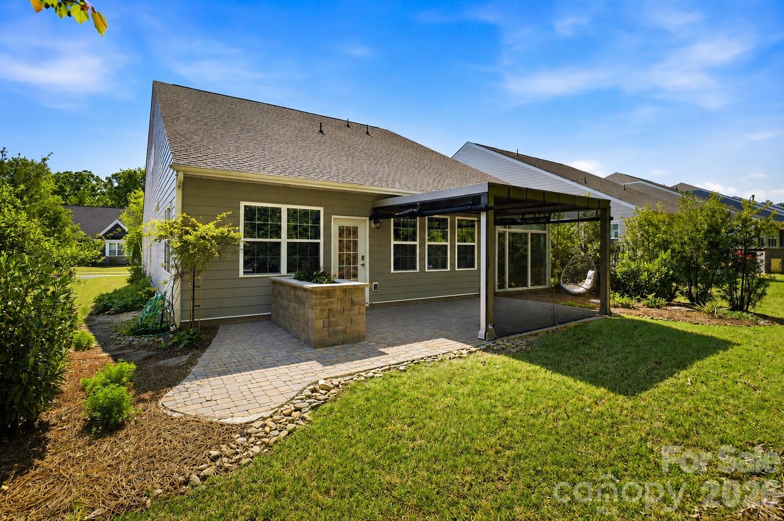 Enjoy year-round outdoor living with an extended paver patio and a StruXure motorized pergola featuring integrated lighting, a ceiling fan, heaters, and a rain sensor. - 124 Van Gogh Trail, Mount Holly