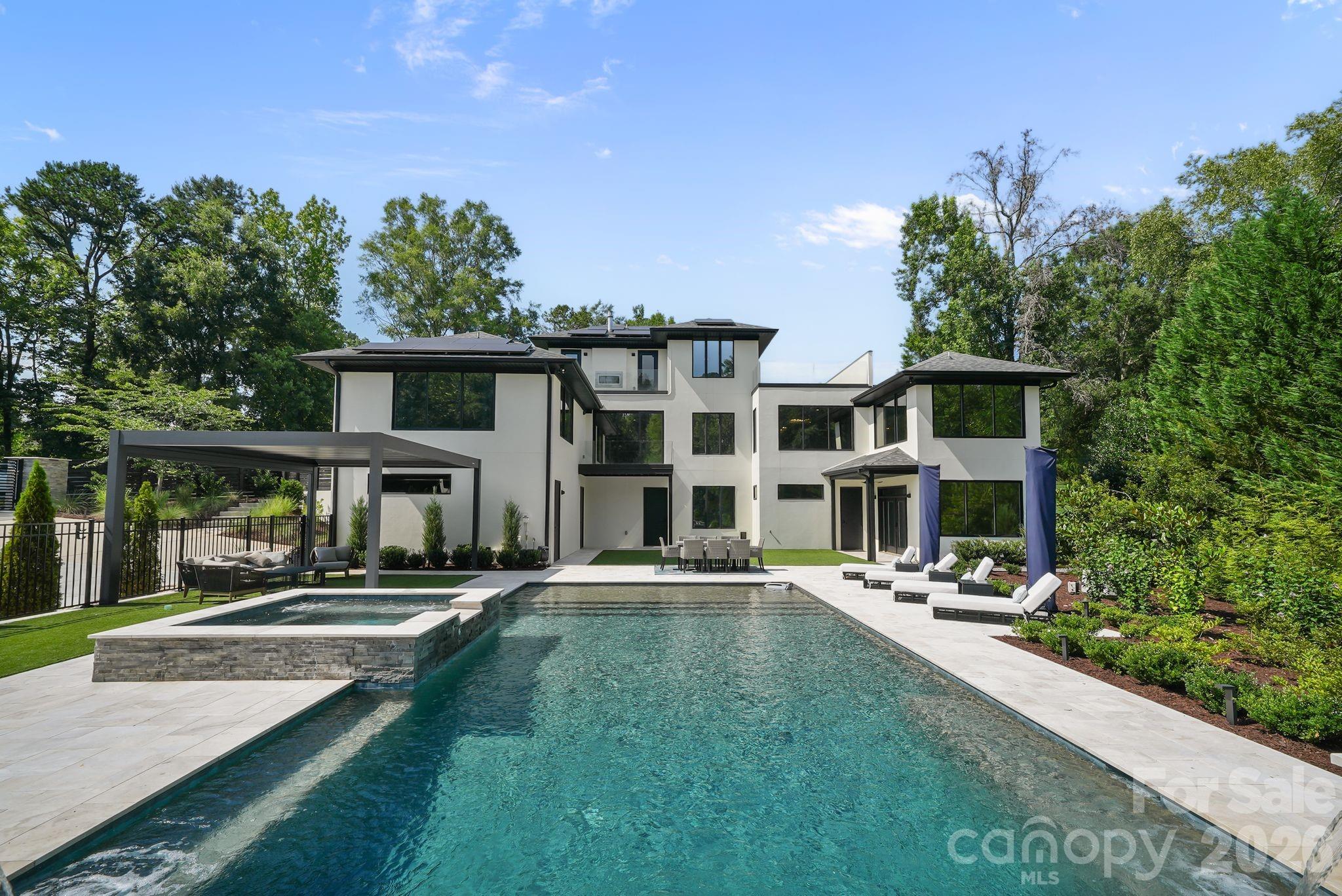 Resort-style pool with sheer-descent waterfalls, tanning ledge, built-in benches, and leathered marble deck - 1064 Greylyn Drive, Matthews